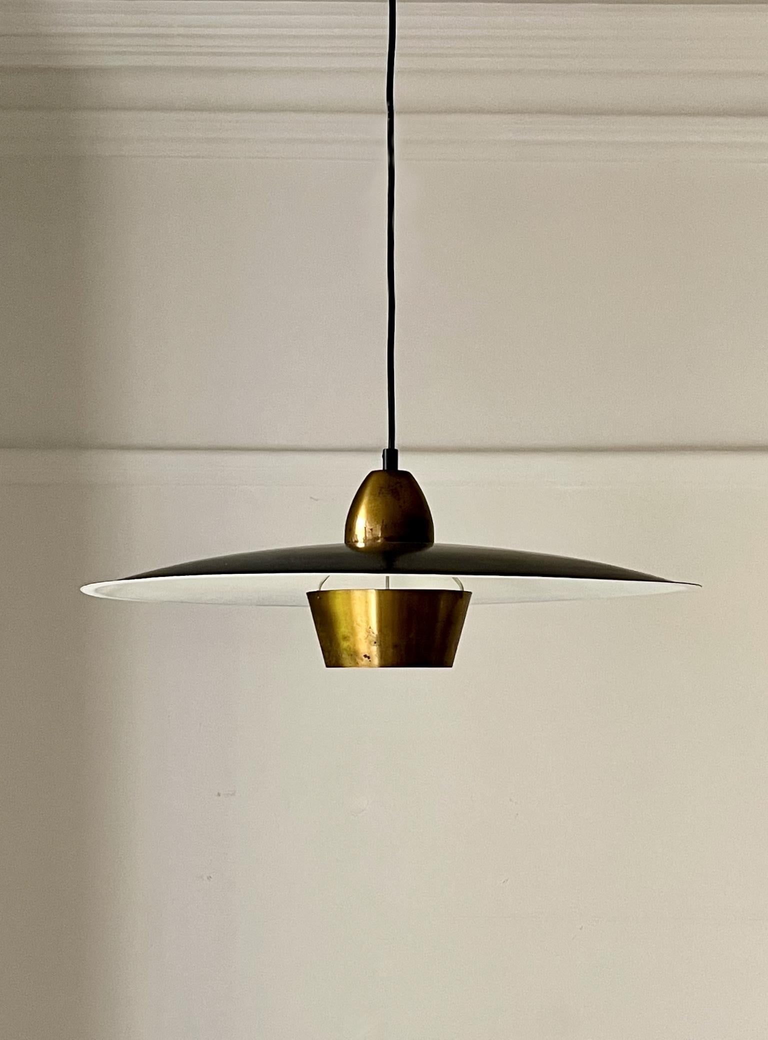 Suspension du milieu du XXe siècle réalisée par l'orfèvre Sigvard Bernadotte (1907-2002) pour Bergboms (Suède), modèle T-21.

Une lampe suspendue simple et élégante en métal peint et en laiton. Le grand abat-jour - noir en haut et blanc en bas -