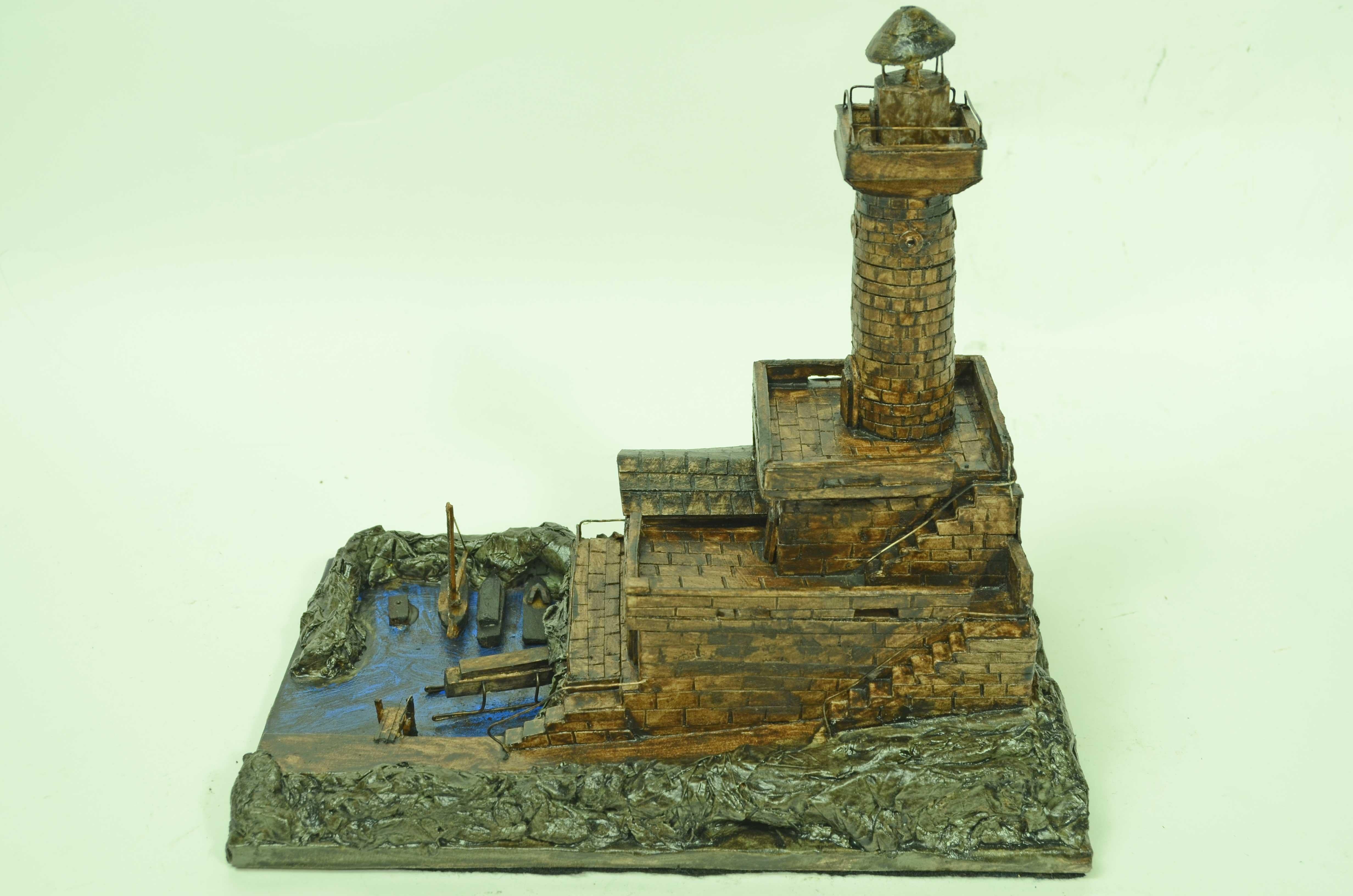 Modelino in scala di faro, realizzato negli anni Cinquanta in cartapesta, gesso e legno, su base lignea.
Über einem Gebäude befindet sich ein zylindrischer Turm, der sich nach oben hin verjüngt. Im oberen Teil befindet sich die Laterne, in der die