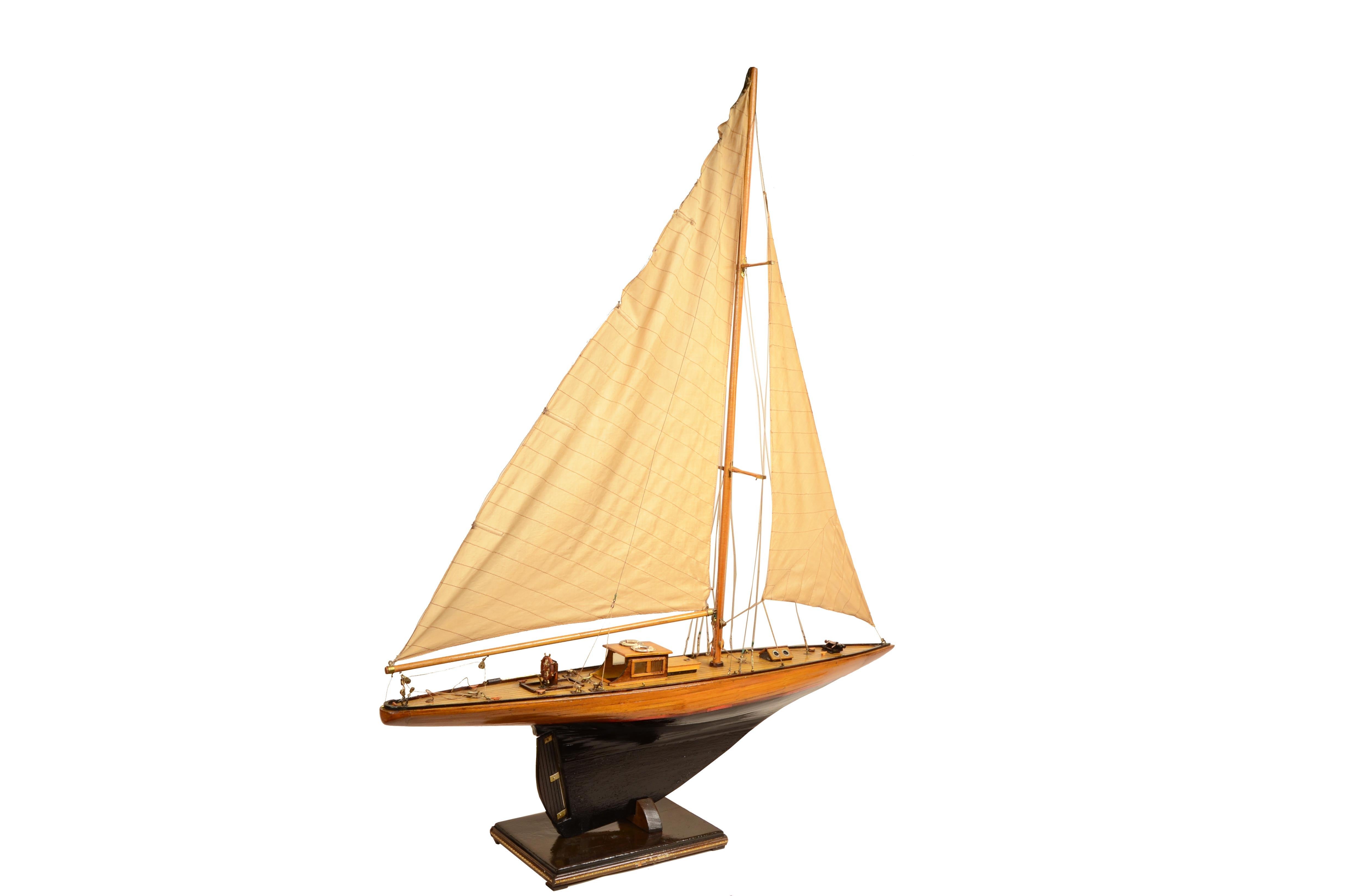 Scale model of a recreational sloop equipped with a mast with mainsail and jib.
Early 20th-century English manufacture, made of wood, brass, rope, and cloth on wooden base, dark wood living work, light wood dead work with red separating strip.
Bon