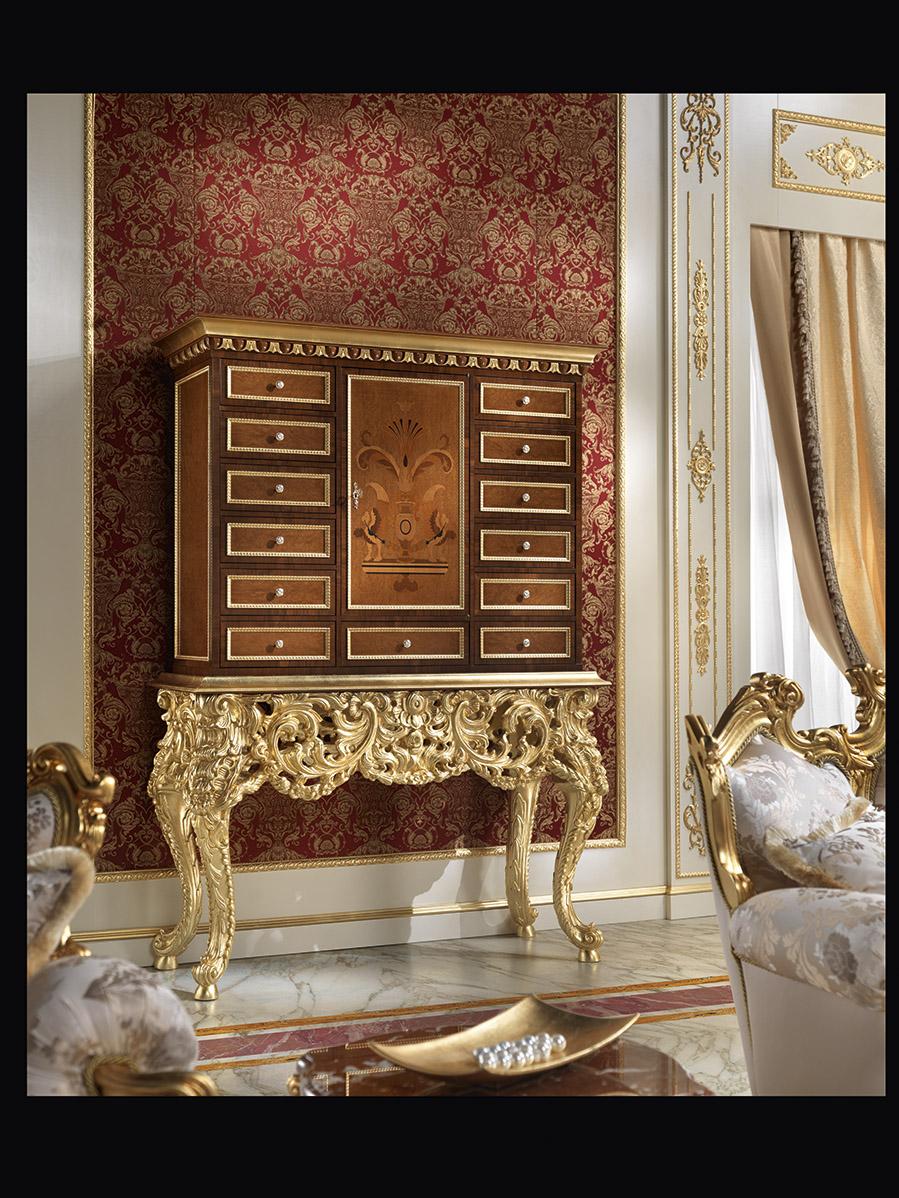 Magnificent 13-drawers coin cabinet, with a solid wood high-end luxury structure decorated with breathtaking hand carved squiggles featuring shiny gold leaf applications. The upper wooden case presents a dark walnut finishing and the drawers are