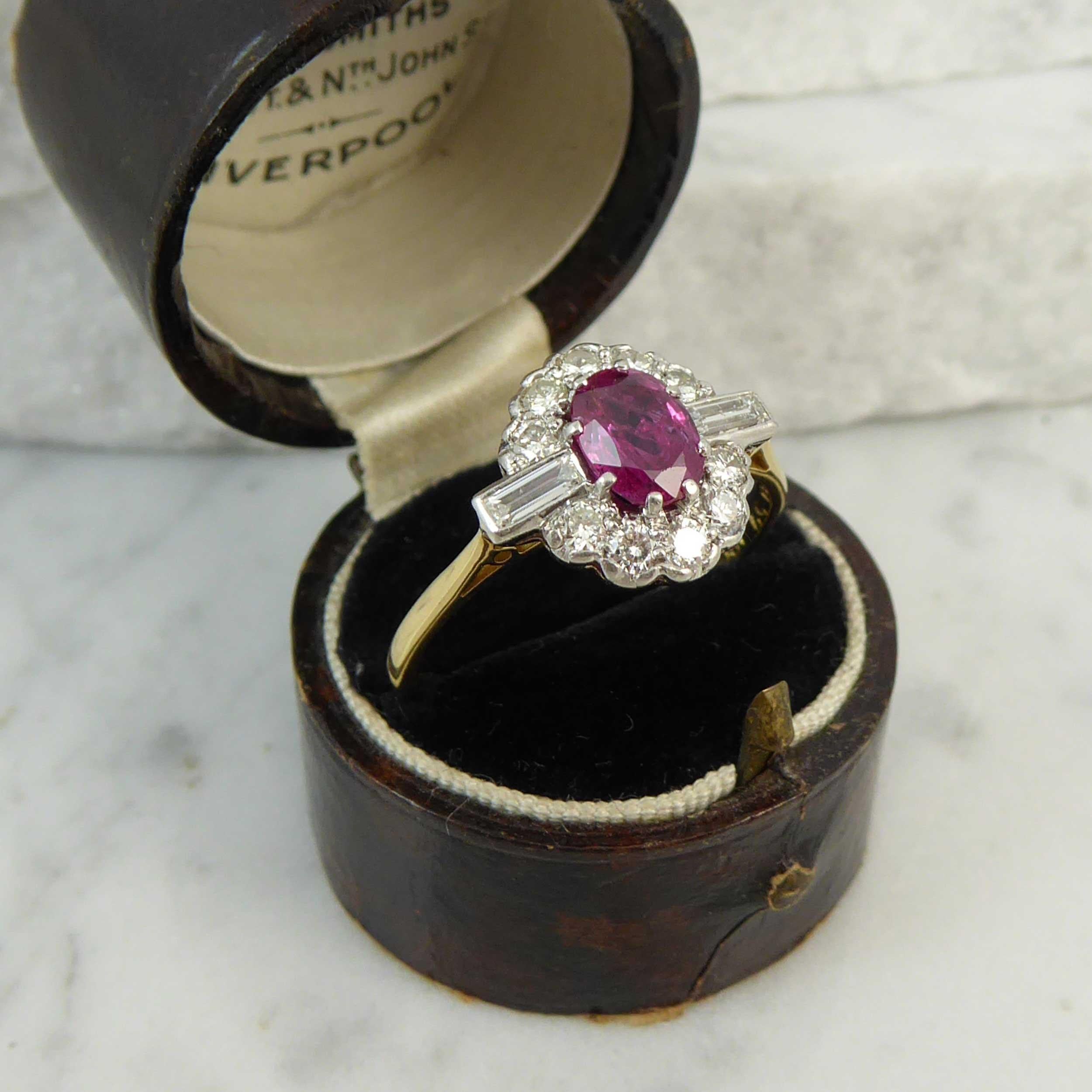 Modern, pre-owned ruby and diamond ring in a traditional style.  The ring is set to the centre with an oval mixed cut ruby, measuring approx. 6.74mm x 5.04mm x 3.45mm deep, and held in white claw settings to a surround of 10 round brilliant cut
