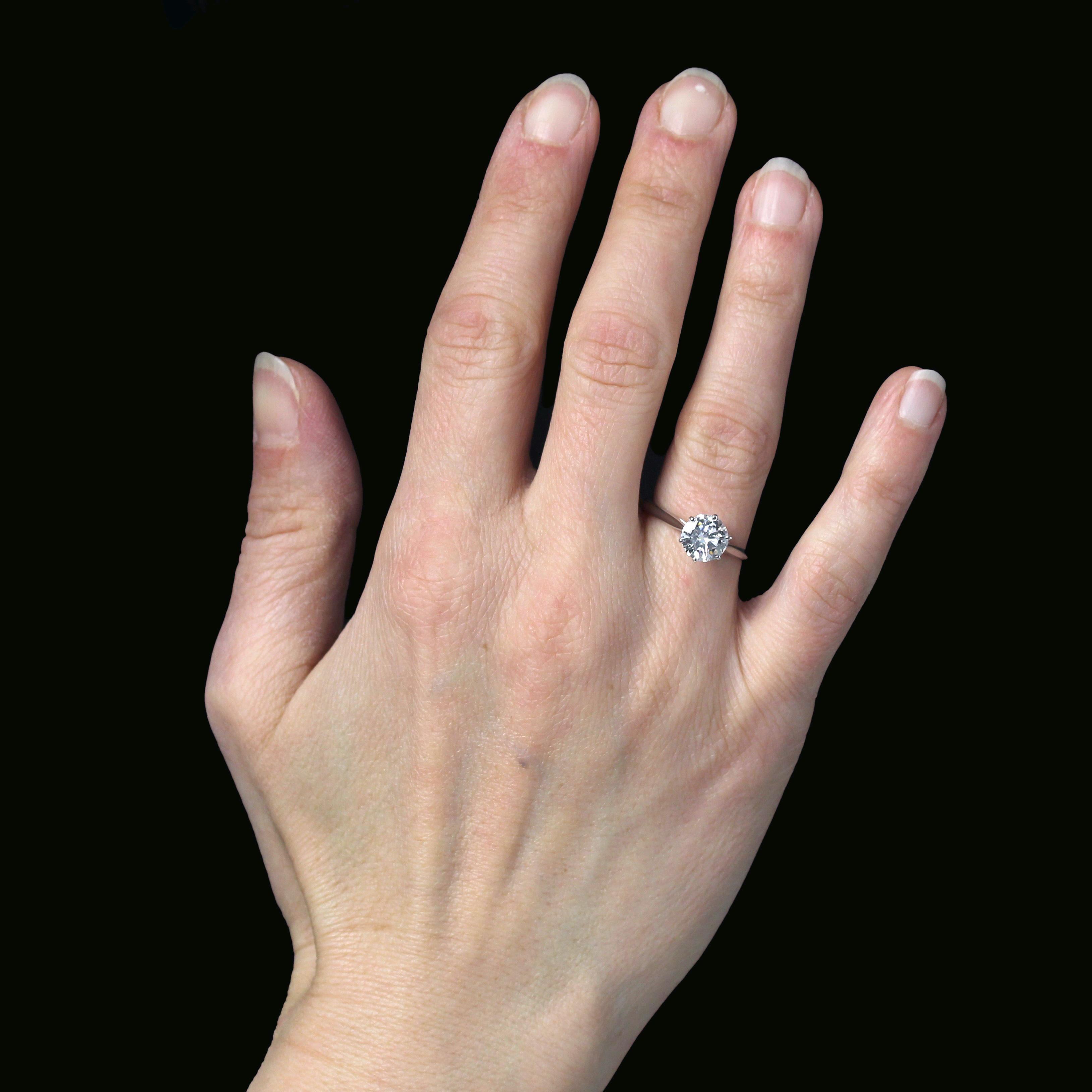 Anello in oro bianco 18 carati, marchio di fabbrica con testa d'aquila.
Un anello solitario con un semplice e sottile anello d'oro che regge un cestino con sei griffe e un diamante taglio brillante.
Peso totale del diamante: 1,21 carati circa.