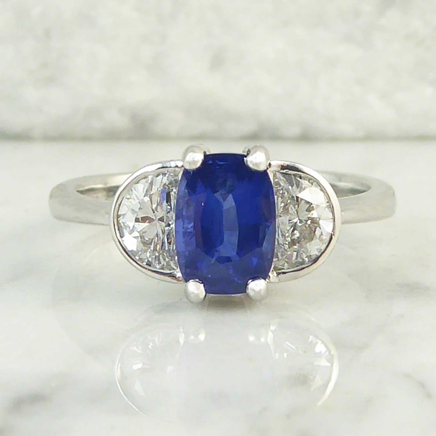 We have had this pretty and unusual modern sapphire and diamond ring made in our workshops.  It is set to the centre with an oval mixed cut sapphire of rich blue colour (probably heat treated as the vast majority of sapphires are) but what set this