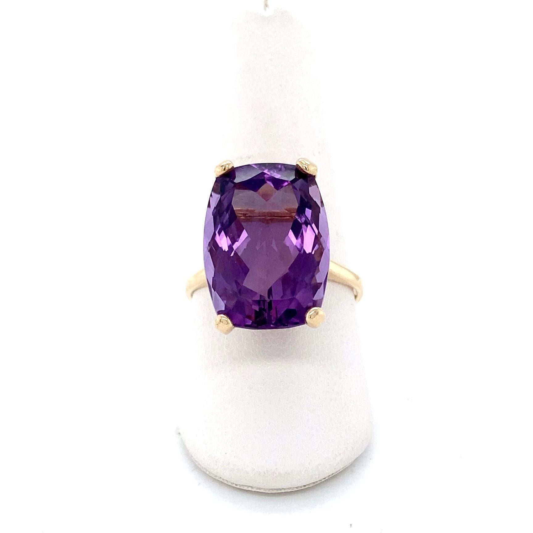 Cette grande bague de style moderne en or jaune 14 carats est ornée d'une époustouflante améthyste de taille coussin d'environ 12,45 carats qui rayonne d'une teinte riche et royale. La taille coussin a été facettée de manière experte afin de