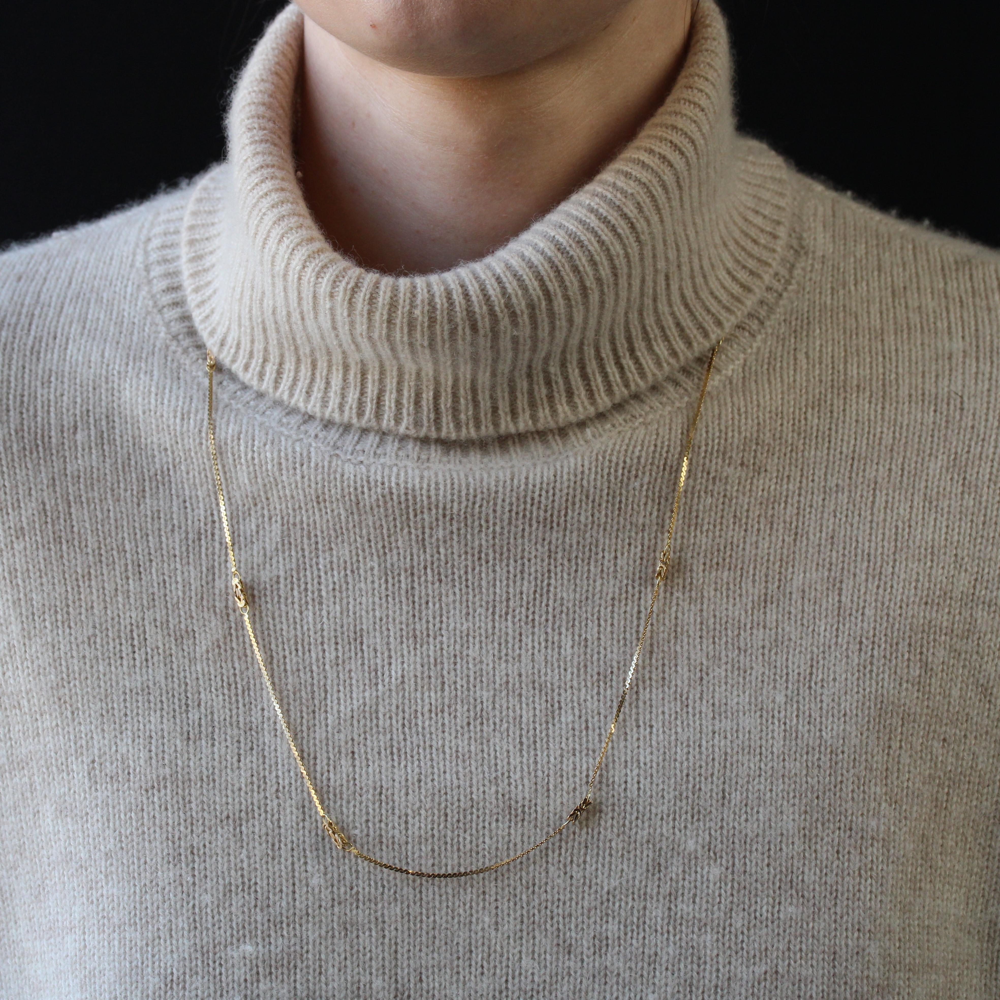 Collana in oro giallo 14 carati, marchio di conchiglia.
Una lunga catena di seconda mano, caratterizzata da un motivo a rete fantasia intervallato da 8 motivi in rilievo. La chiusura è a molla.
Lunghezza della catena: 63,5 cm circa, larghezza della