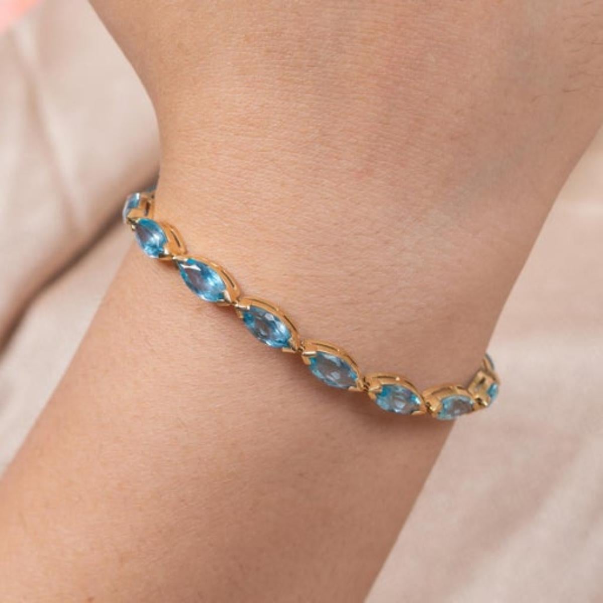This Modern Marquise Blue Topaz Tennis Bracelet in 14K gold showcases 16 endlessly sparkling natural blue topaz, weighing 18.9 carats. It measures 8 inches long in length. 
Blue topaz helps to improve communication and self expression. 
Designed
