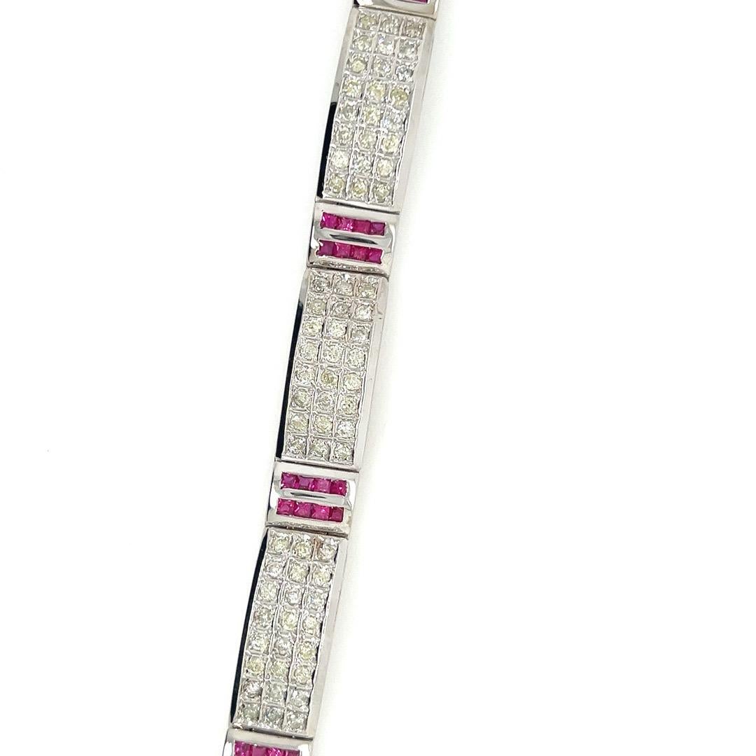 Ein prächtiges Armband aus 14 Karat Weißgold, besetzt mit etwa 10 Karat natürlichen Diamanten und Rubinen.

Das Schmuckstück ist mit 168 natürlichen, runden Brillanten von insgesamt ca. 5 Karat besetzt, die als K-L in der Farbe und I1-I2 in der
