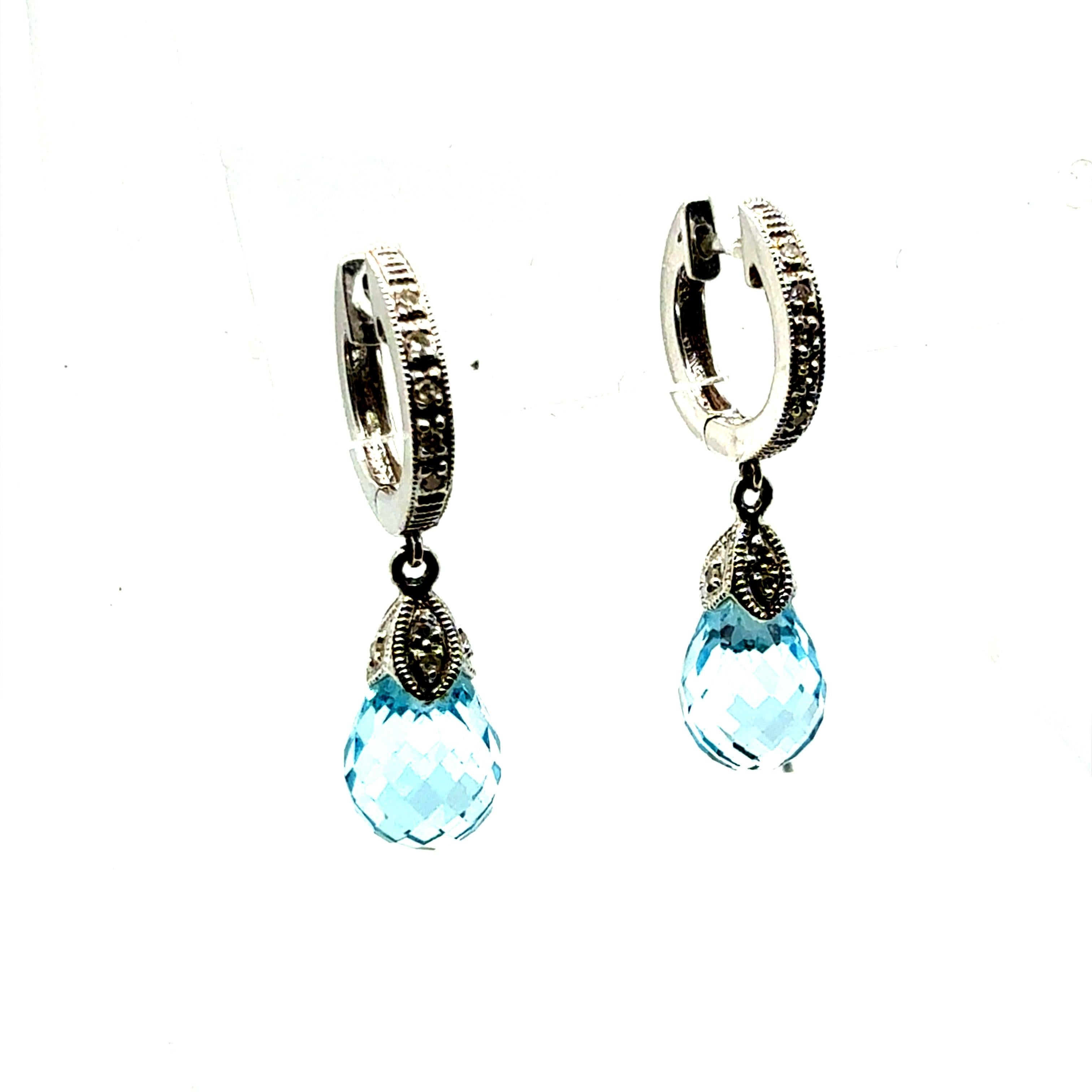 Boucles d'oreilles modernes en or blanc 14K mettant en valeur des briolettes de topazes bleues vives, chacune mesurant environ 7,1 mm de large. Les boucles d'oreilles mesurent 1 pouce de long, les arceaux supérieurs étant sertis de 18 diamants