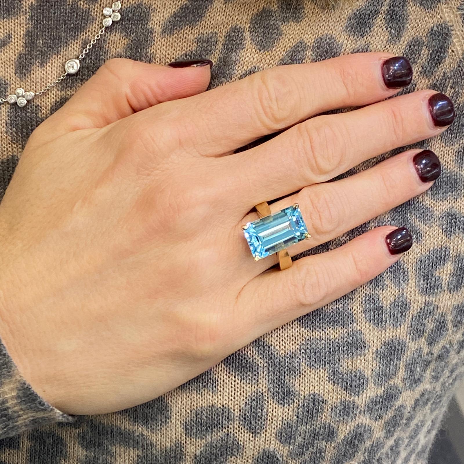 Modern aquamarine cocktail ring fashioned in 14 karat yellow gold. The bright blue aquamarine measures 10.5 x 18mm and is approximately 12 carats. The ring is currently size 6.25 (can be sized).