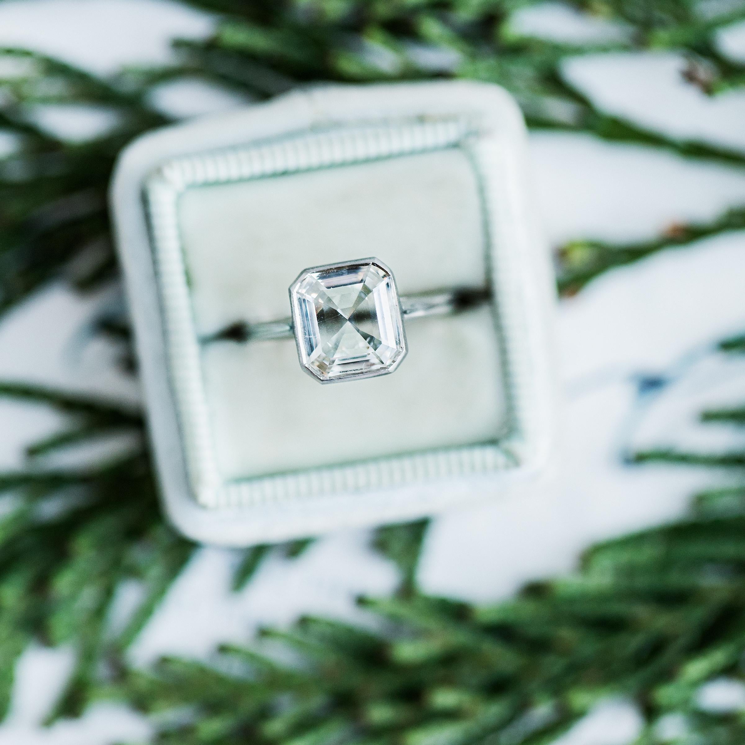 This is a wonderful modern engagement ring handcrafted in platinum by our master jeweler in downtown Los Angeles. This chic ring centers a bezel set diamond accompanied by an EGL certificate stating the 1.57ct Emerald Step Cut diamond is graded H