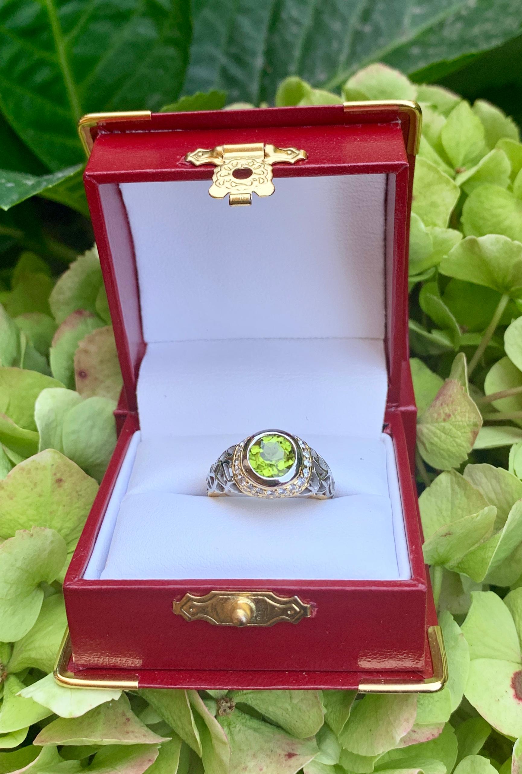 In this striking, custom made ring, a vivid chartreuse green round peridot gemstone is bezel set in 14 karat yellow gold and surrounded by pave set round white diamonds. The shoulders of the ring feature a modern abstract openwork pattern in