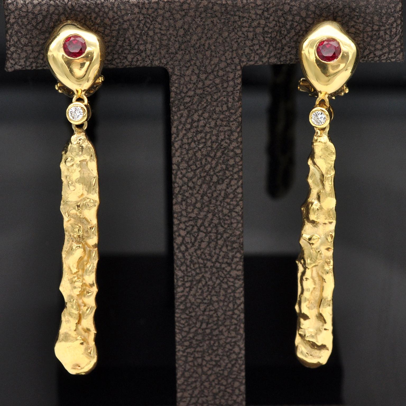 Modernist 18KT yellow gold dangle earrings: the top is shiny yellow gold set with a vivid red round ruby. a bezel set white diamond makes the junction with a long textured sculpture like dangling part.
Rubies : approximately 0.60 carat
Diamonds: