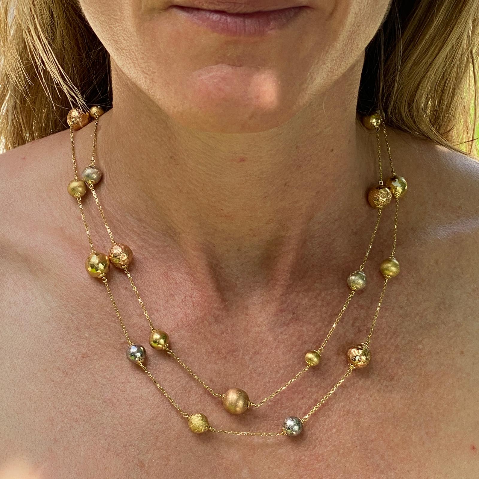 Modern two strand necklace fashioned in 18 white, yellow, and rose gold. The necklace features high polilsh and satin finish textured gold balls, and measures 18 inches in length (one strand is slightly longer). Great classic staple that matches