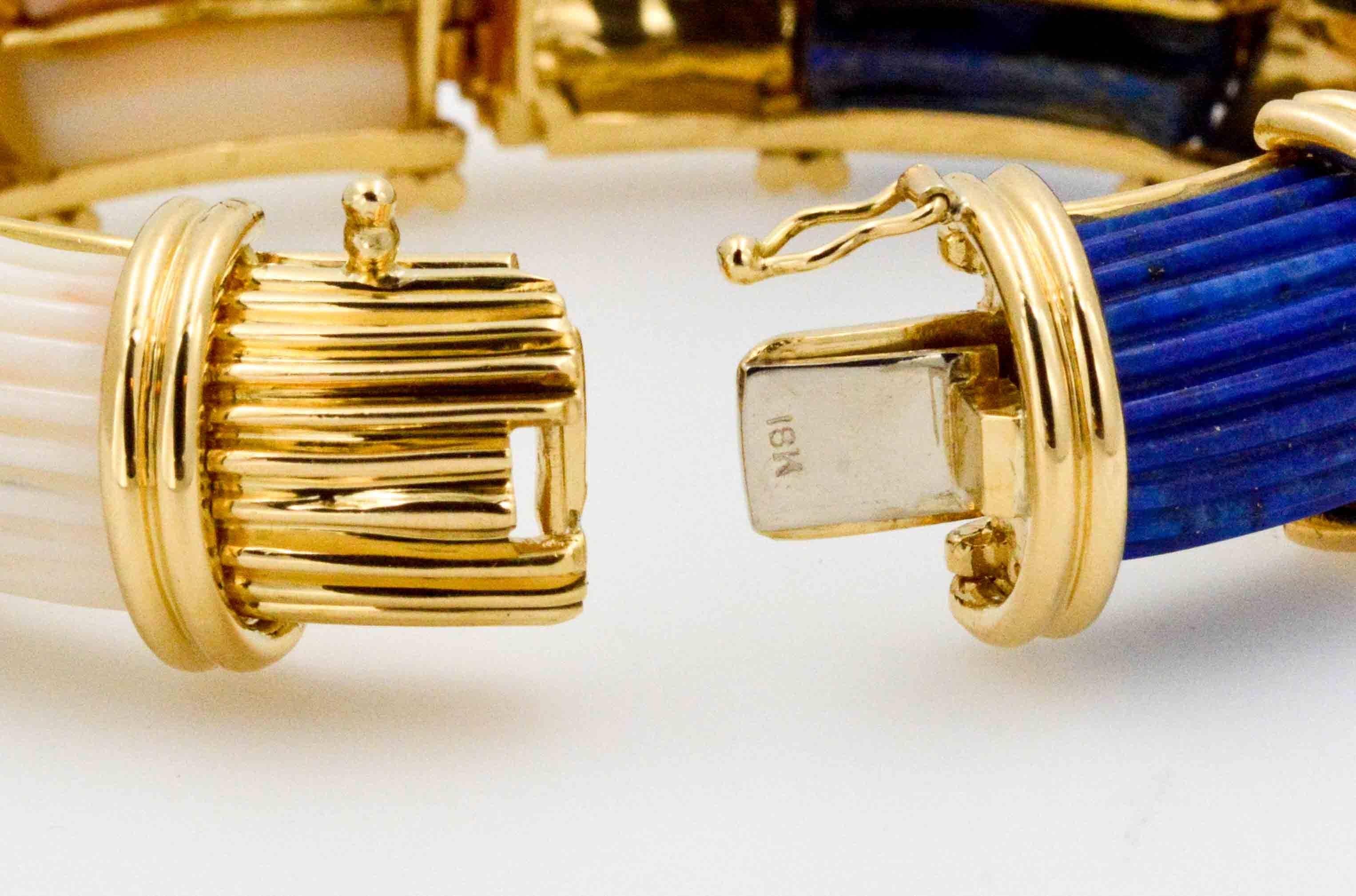 Classically elegant with a modern angle is this 18 karat yellow gold bangle bracelet created in the 1980's. Expertly carved white coral and blue lapis alternate between carved 18 karat yellow gold bars.  This stunning gold bangle bracelet fits a