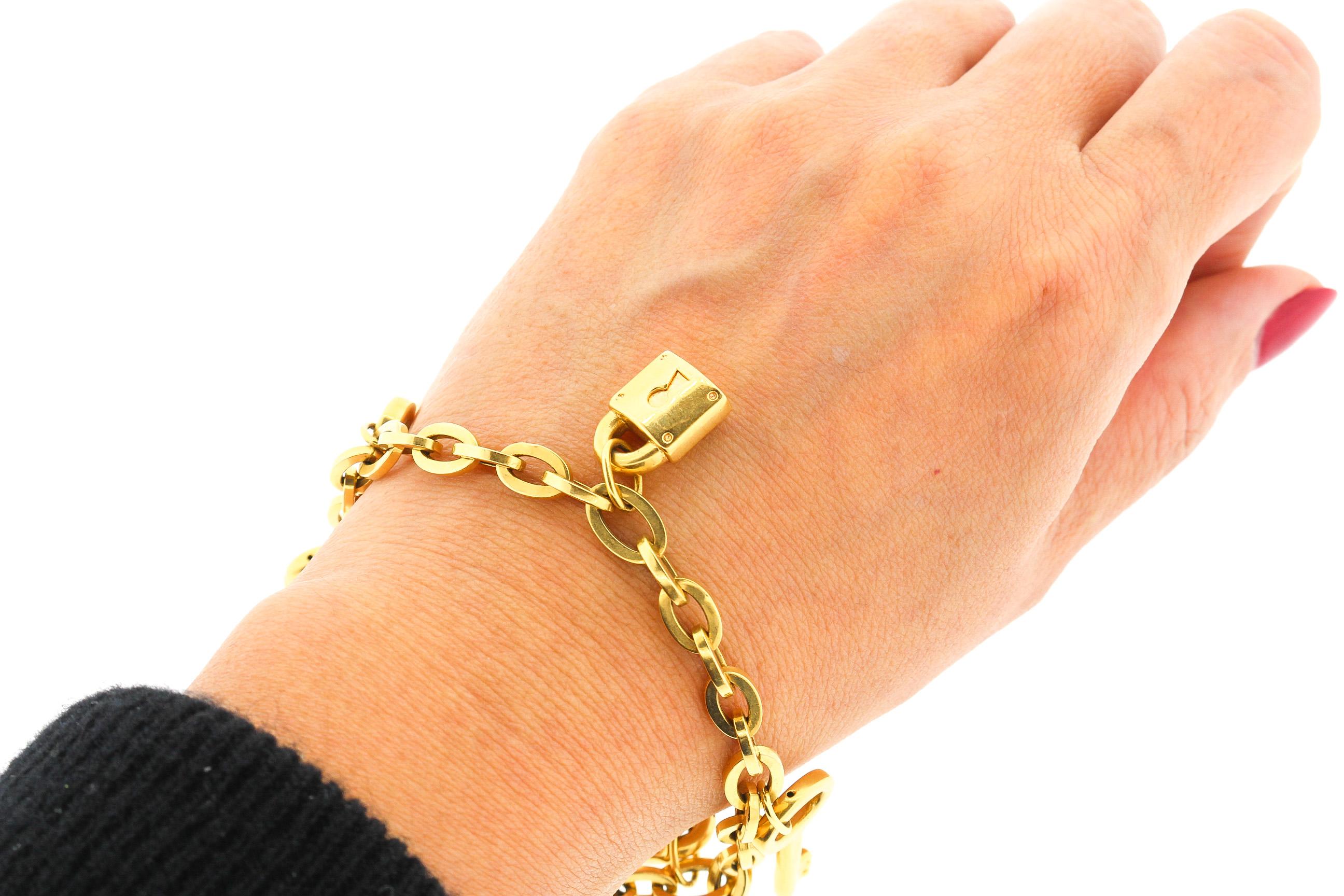 A wearable hollow form gold 18k yellow gold link charm bracelet with alternating key and padlock charms. The bracelet has Italian hallmarks and was likely made in the 1990s. The oval link chain of the bracelet is very attractive and the charms well