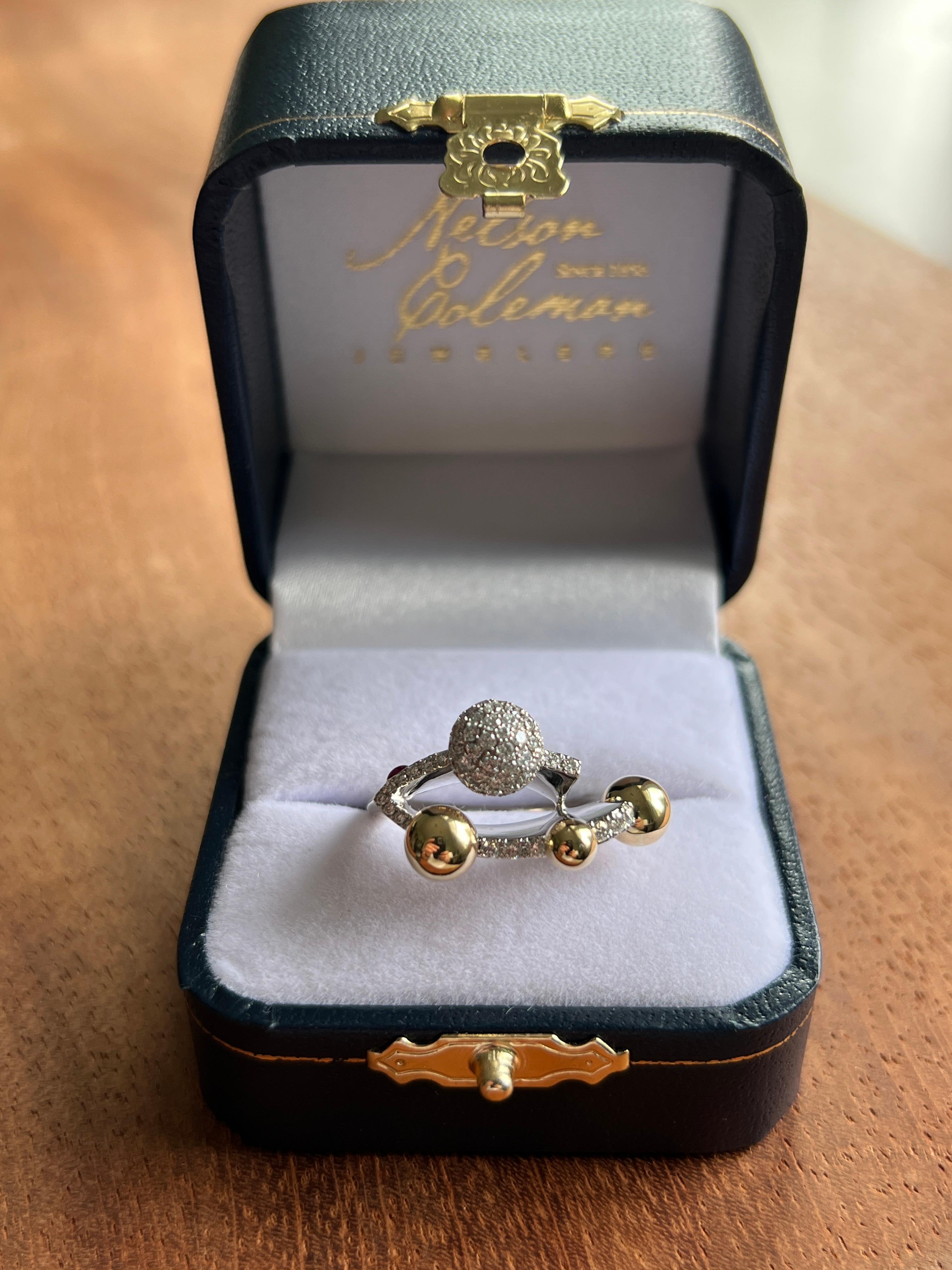 Questo anello contemporaneo in oro giallo e bianco 18 carati presenta una fusione scultorea di eleganza moderna e forma giocosa. Al centro, una sfera di diamanti incastonata a pavé brilla con sessantaquattro diamanti tondi brillanti per un totale di