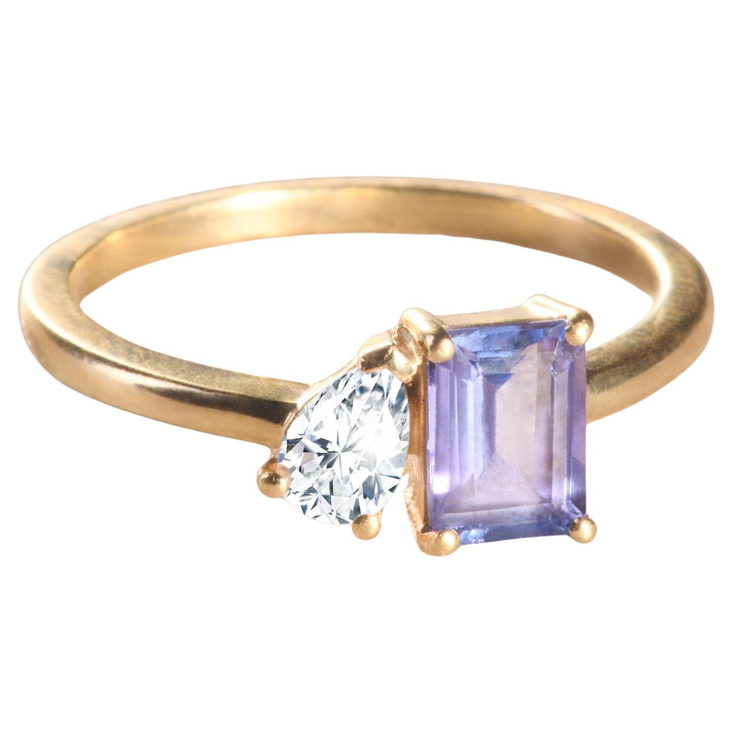 Modern 18k yellow gold ring with a emerald-cut Tanzanite and a pear-cut diamond.