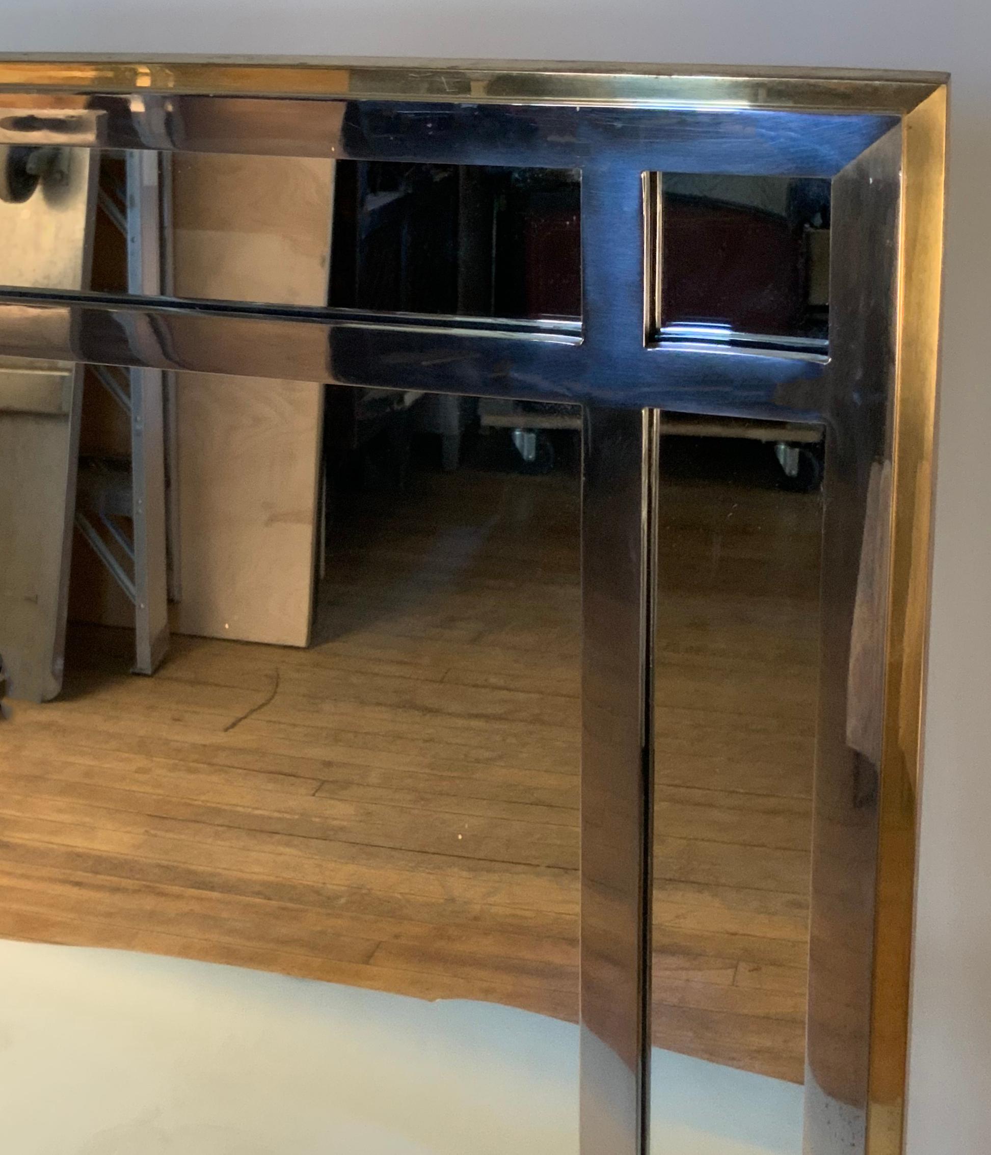 A very handsome vintage 1970s wall mirror with a frame of heavy brass and a grid front around the edges in chrome. Great design and craftsmanship.