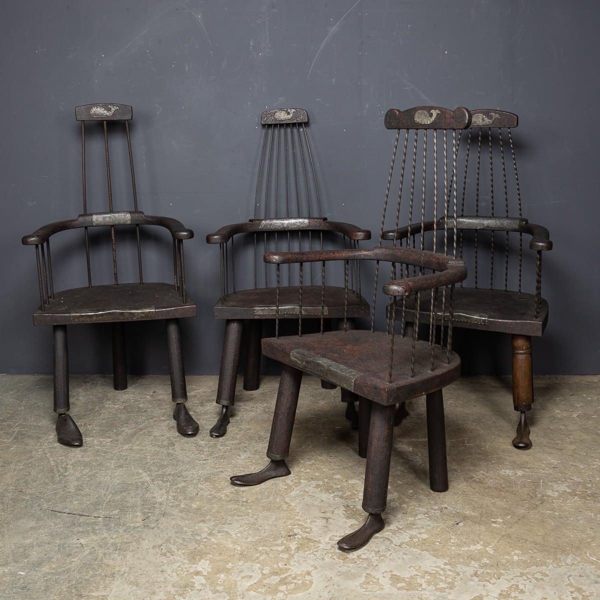 Un juego de cuatro sillas de arlequín del siglo XXI, obra de Martin Scorey, fabricadas en madera recuperada y hierro, con singulares moldes de zapatero a modo de patas. Estas sillas ofrecen una sorprendente mezcla de encanto rústico y diseño