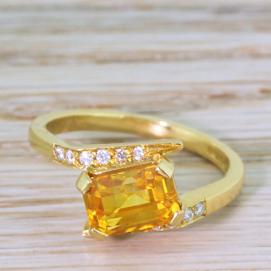 The most glorious ring. The orange sapphire in the centre is a gleaming and glowing slightly amber orange, the colour of which is perfectly complimented by the yellow of the 18k gold setting. The stone is secured in a four claw open collet with sits