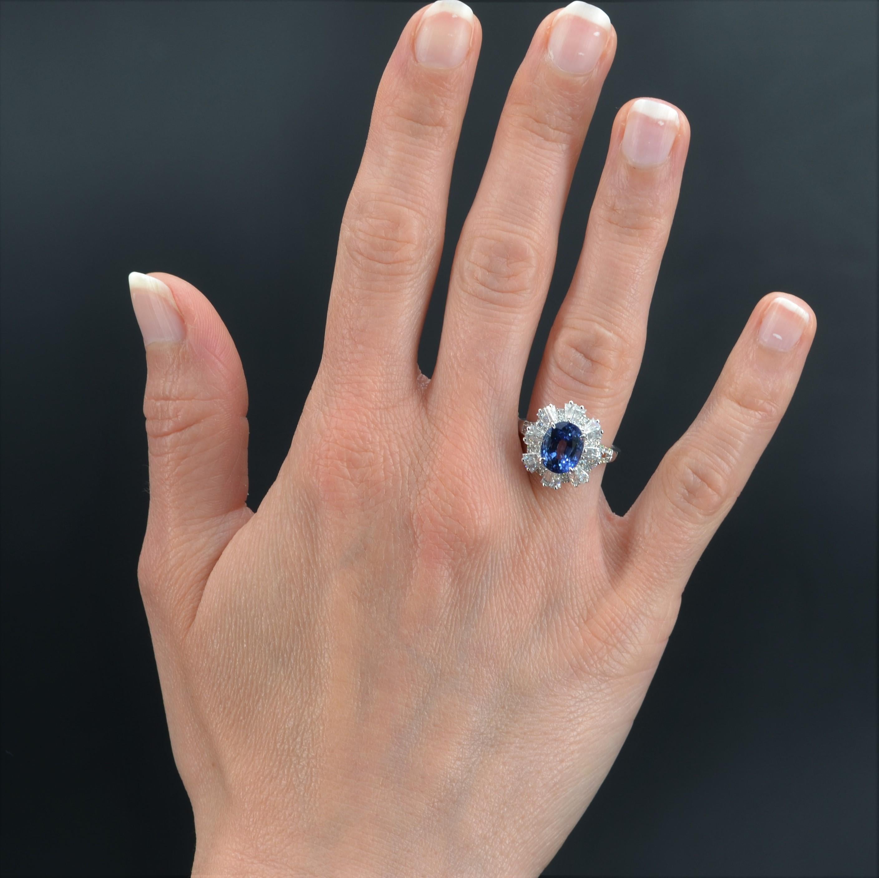 Ring in 18 karat white gold, eagle head hallmark.
Magnificent skirt ring, it is adorned on its top with an oval blue sapphire in a trapezoidal diamond setting alternated with modern brilliant- cut diamonds. The start of the ring is a fork set on