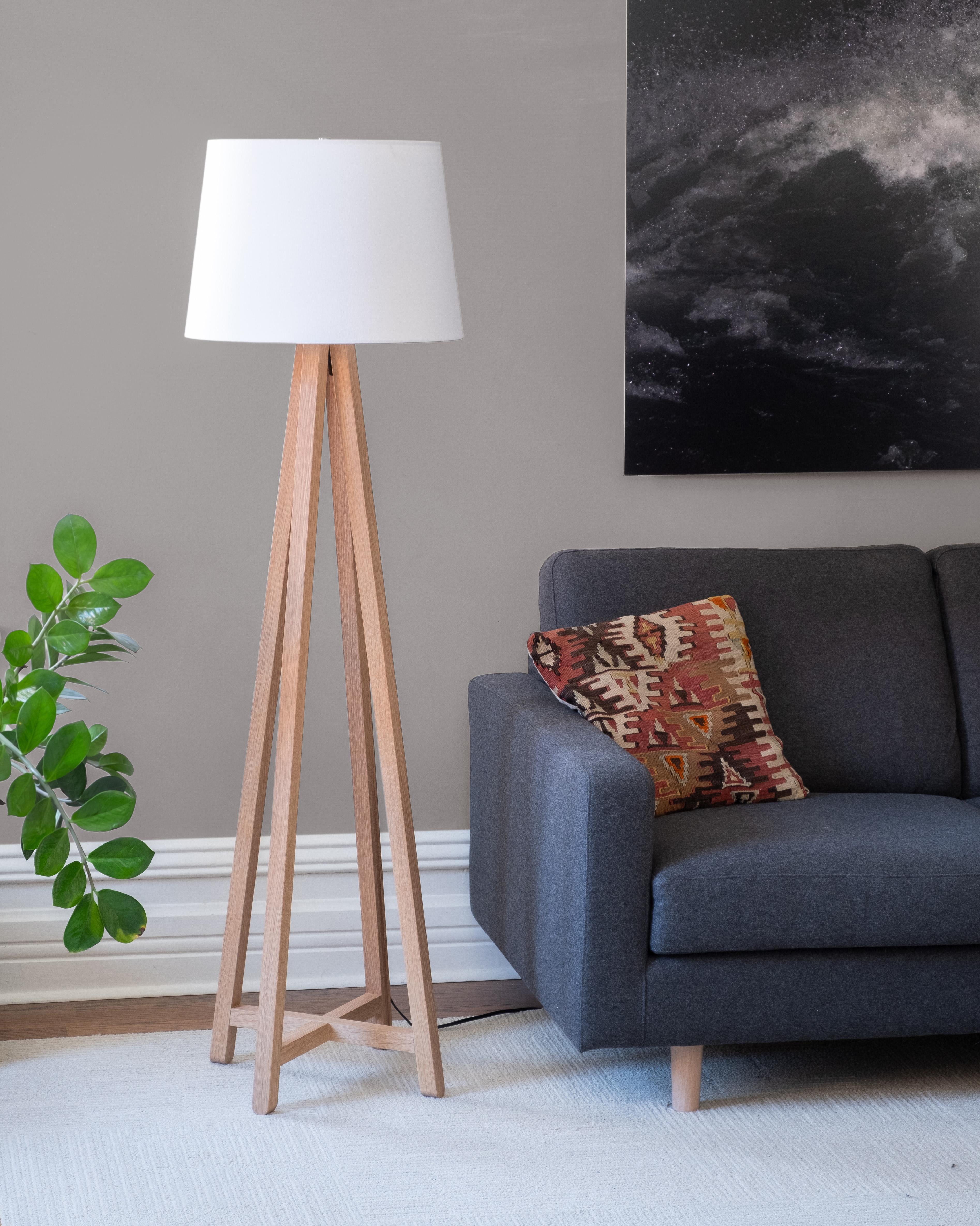 The Alpha floor lamp features a conical drum shade supported by a tapered framework of slender wooden legs. The lamp cord is hidden inside one of the legs to maintain a clean, uncluttered appearance.

The Alpha is available in two sizes: the