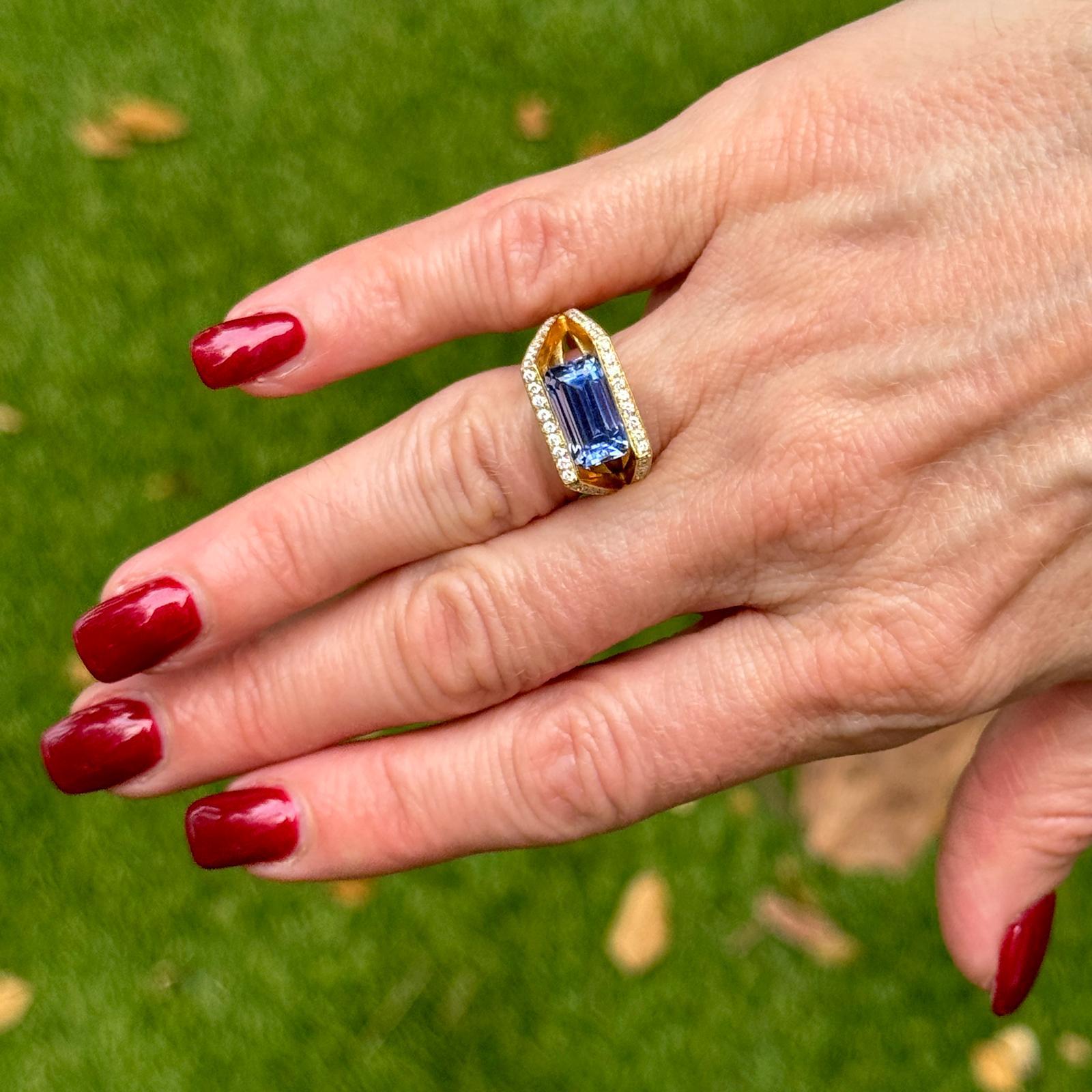 This modern 18 karat yellow gold sapphire and diamond ring by Bony Levy features an approximately 5.00-carat emerald-cut natural blue sapphire set in an elegant east-to-west orientation. The split shank is adorned with 54 round brilliant-cut