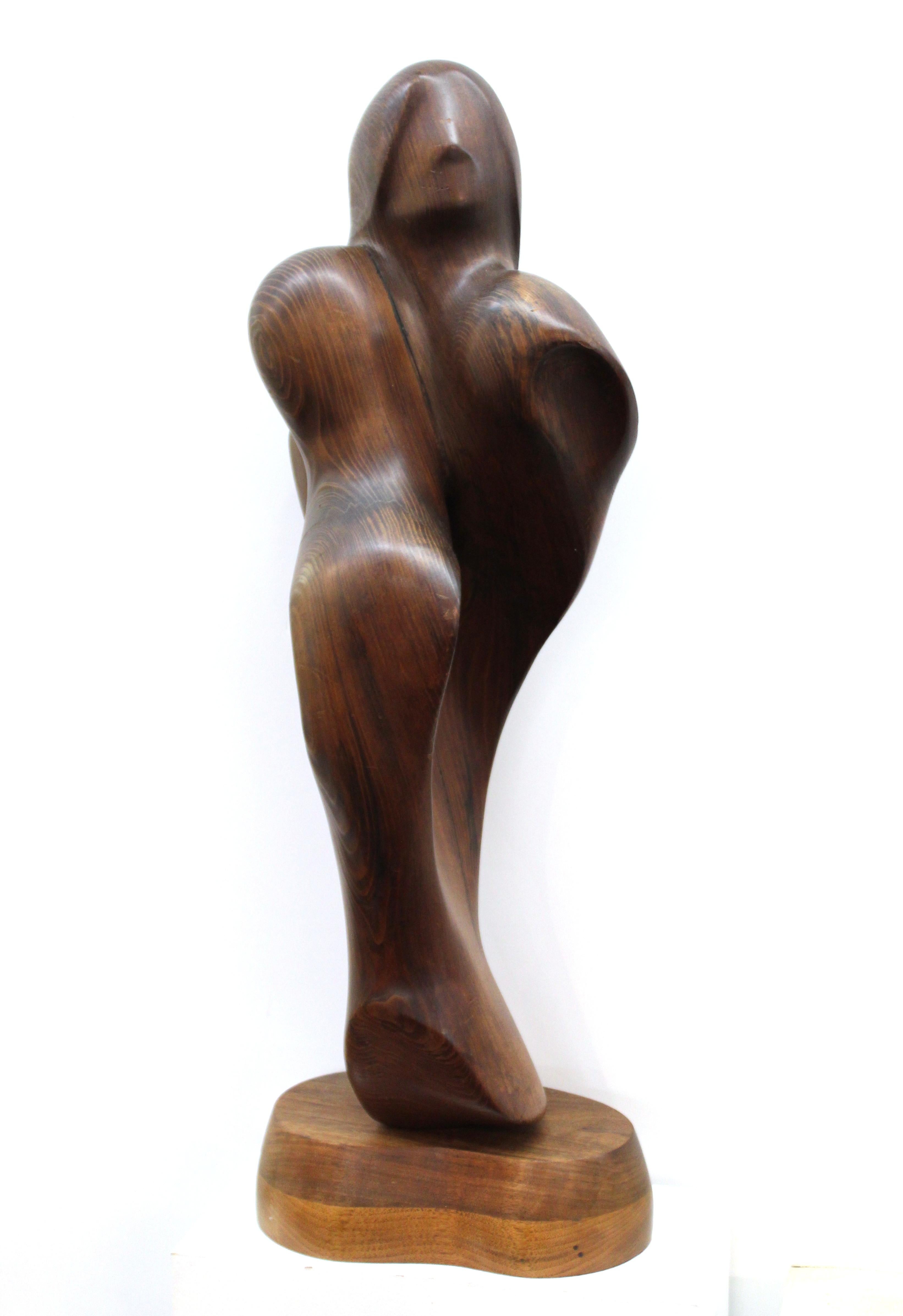 Modern abstract sculpture in carved wood depicting a couple in embrace. The piece is mounted on a rotating base and is signed by the artist on the lower back side 