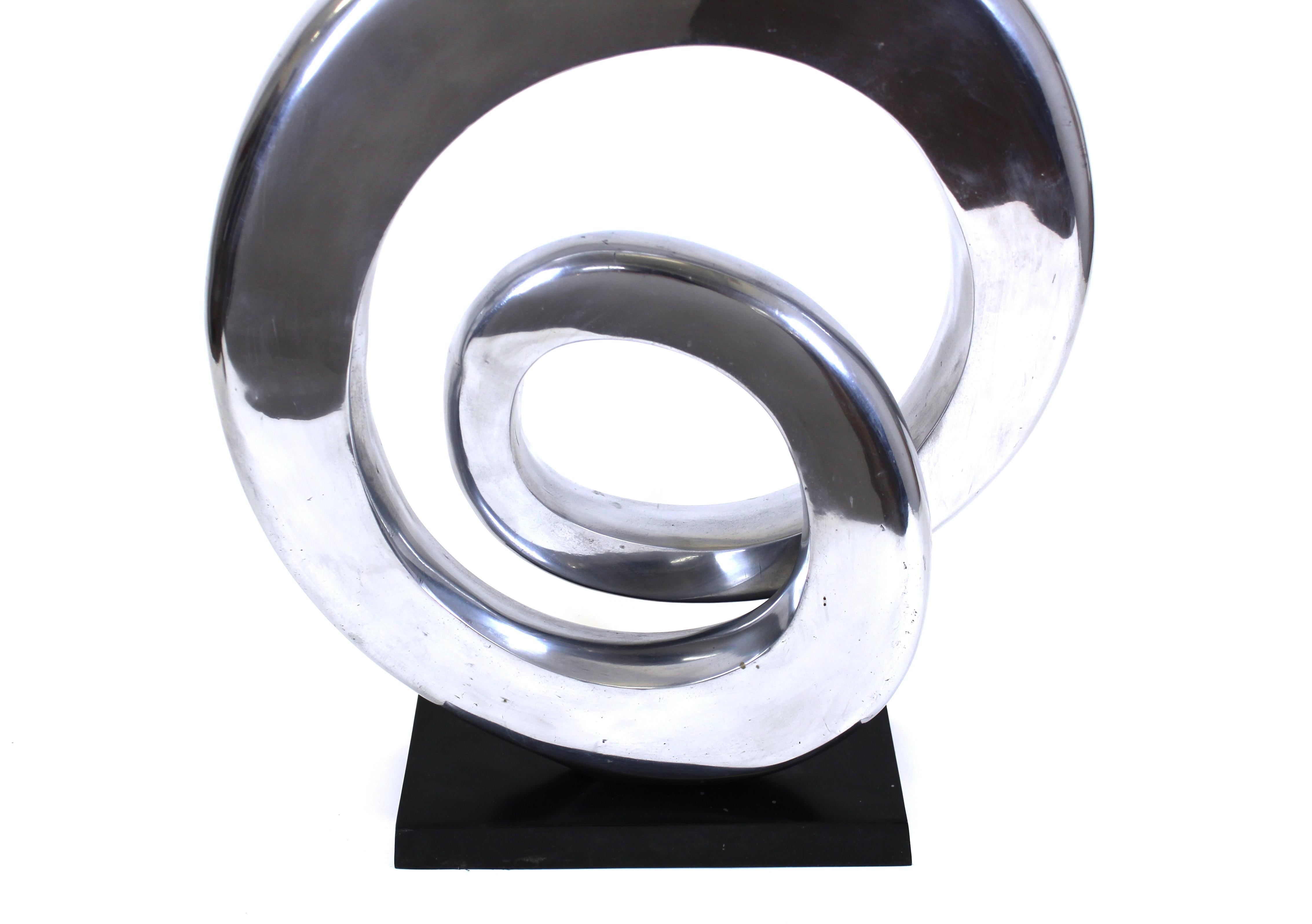 Modern abstract chrome metal ribbon tabletop sculpture mounted on ebonized wood base.