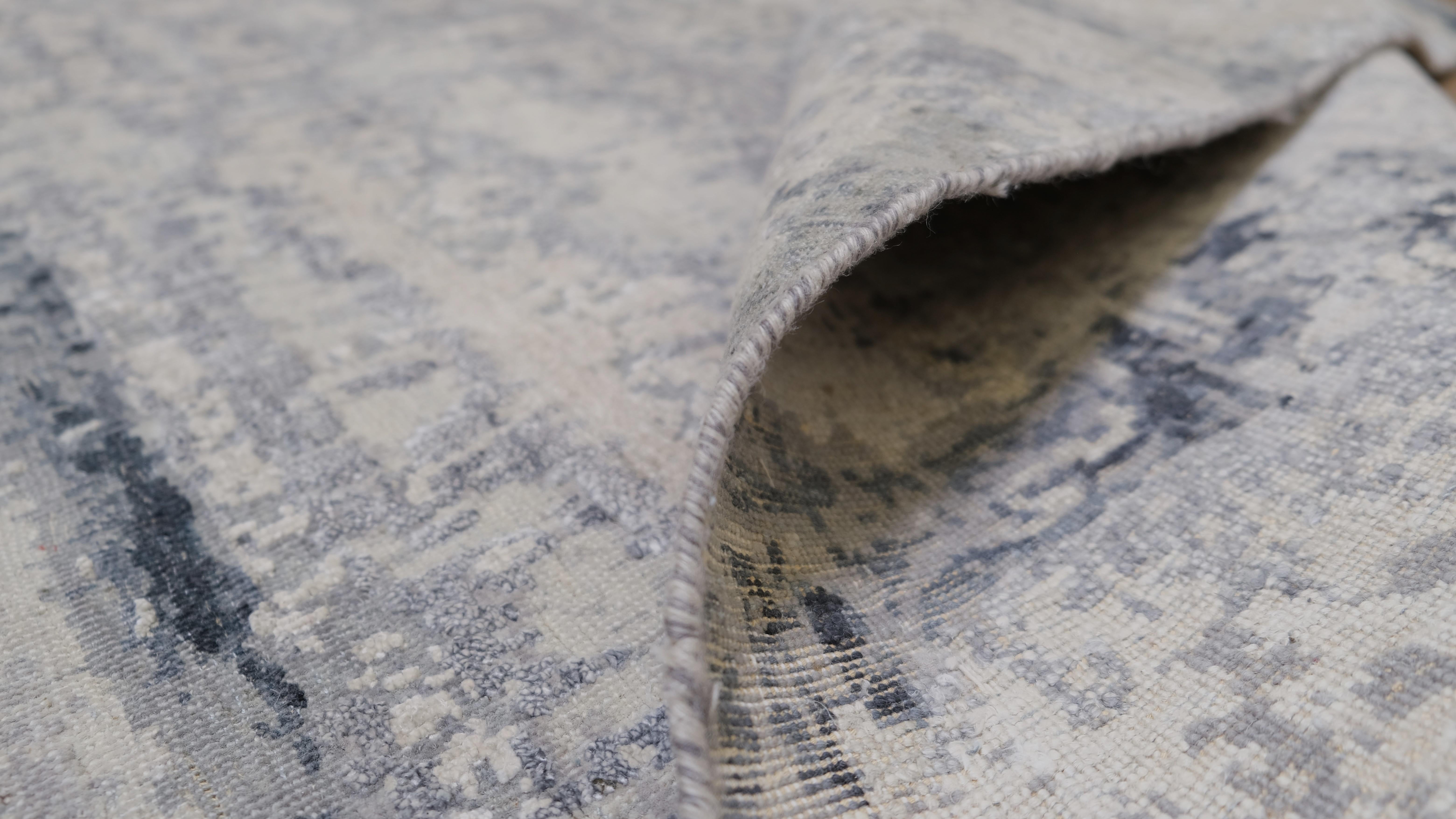 Introduci un'eleganza contemporanea nel tuo spazio con questo tappeto in lana e seta annodato a mano, caratterizzato da uno splendido disegno astratto nelle raffinate tonalità del grigio e dell'avorio. Il sofisticato motivo evoca la texture di