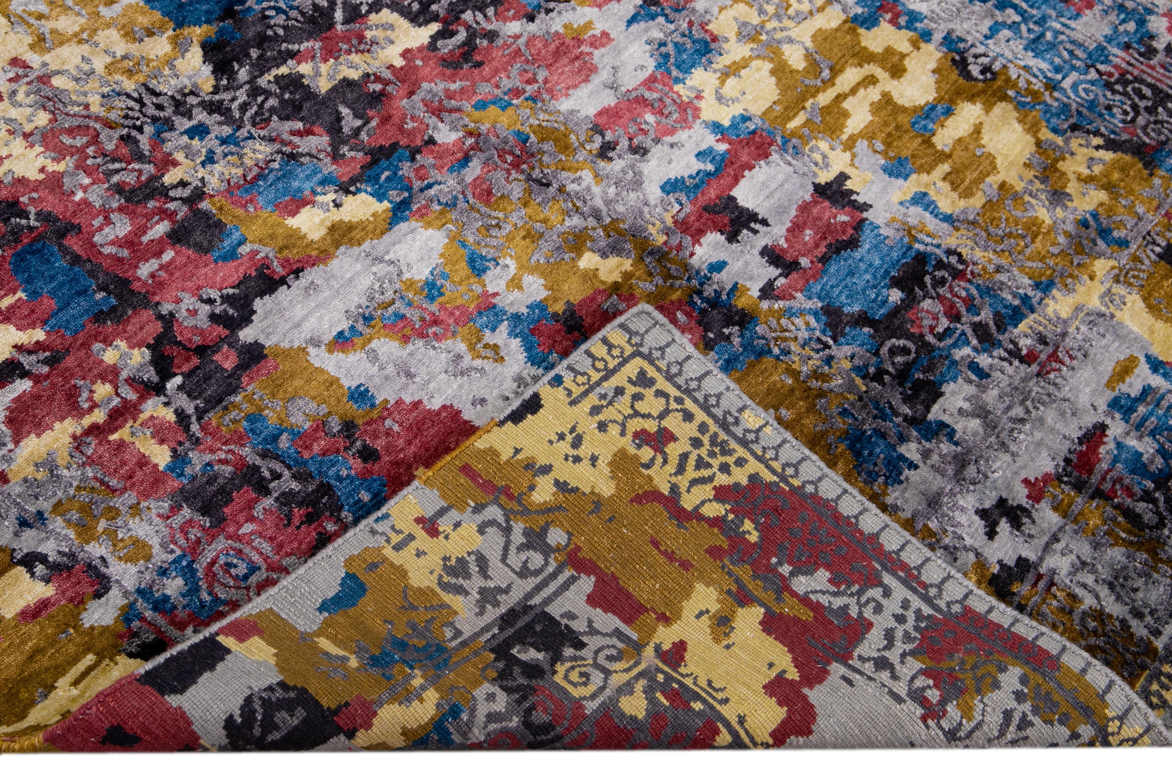 Bellissimo tappeto indiano moderno annodato a mano in lana e seta con campo multicolore. Questo tappeto moderno è caratterizzato da accenti rossi, blu, grigi e dorati e da uno splendido design Abstract.

Questo tappeto misura: 5' x 6'11
