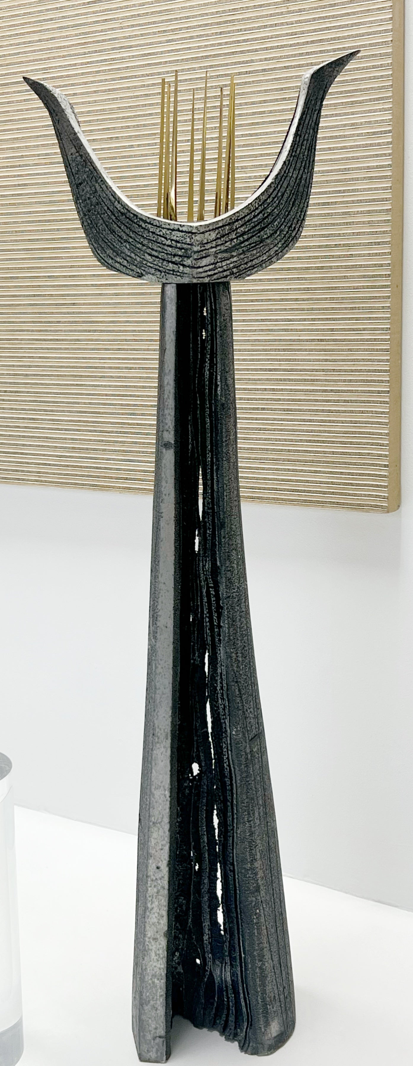 Scultura modernista architettonica caratterizzata da una forma alta e affusolata coronata da un'espressiva cresta alata. Il pezzo è realizzato in metallo fuso fortemente strutturato, la cui superficie presenta striature stratificate e irregolarità