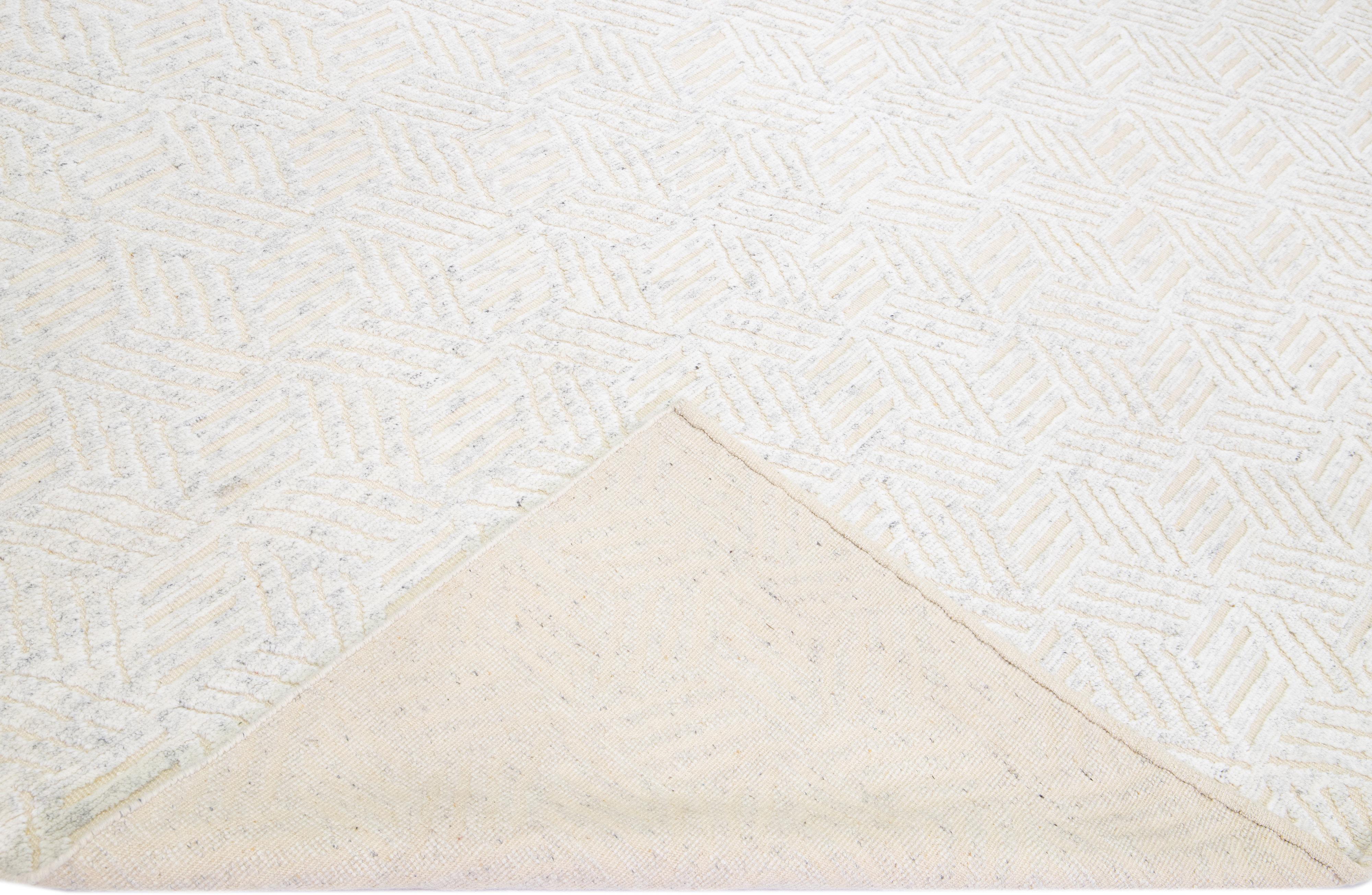 Beautiful modern Moroccan style hand-knotted wool rug with a beige field. This piece has ivory accents with a geometric abstract high pile design.

This rug measures: 10'2'' x 13'11''

Our rugs are professional cleaning before shipping.