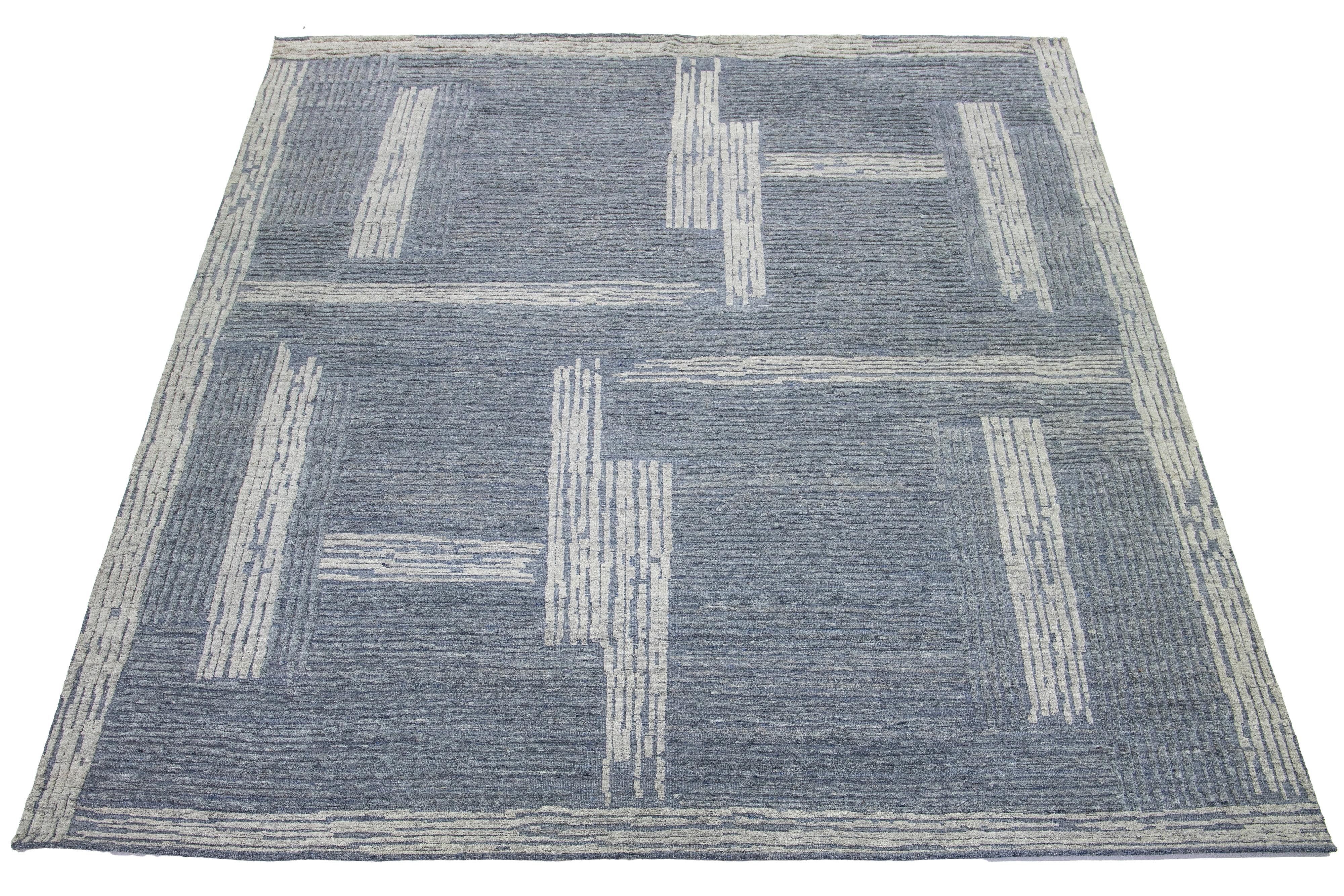 Questo splendido tappeto contemporaneo in lana annodato a mano in stile marocchino è caratterizzato da un accattivante disegno astratto in azzurro e grigio, che aggiunge eleganza e calore a qualsiasi stanza come perfetto centrotavola.

Questo