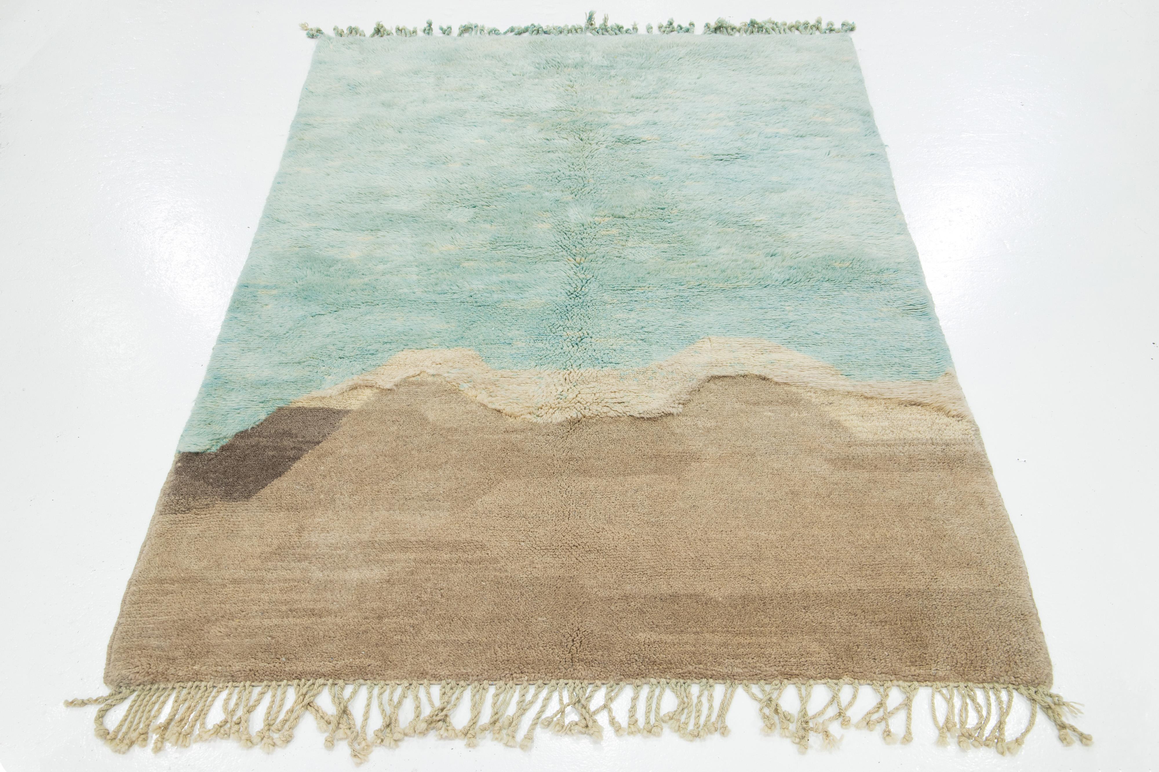 Questo tappeto in lana annodato a mano presenta uno splendido stile marocchino contemporaneo. Presenta un bellissimo disegno astratto con un campo verde e marrone chiaro. Realizzato con la massima precisione, questo tappeto di lusso è un capolavoro