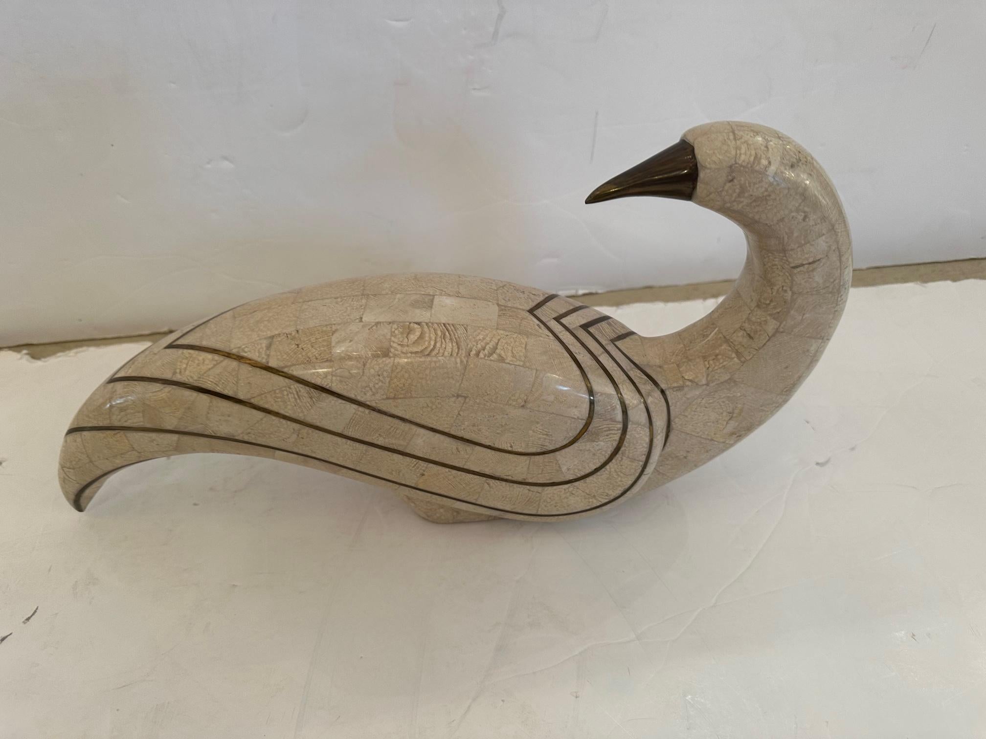 Eye catching elegant tessellated stone sculpture of a dove having sensual lines and abstract form. The beige stone is accented on the body with brass inlay and the beak is a dark brown.
