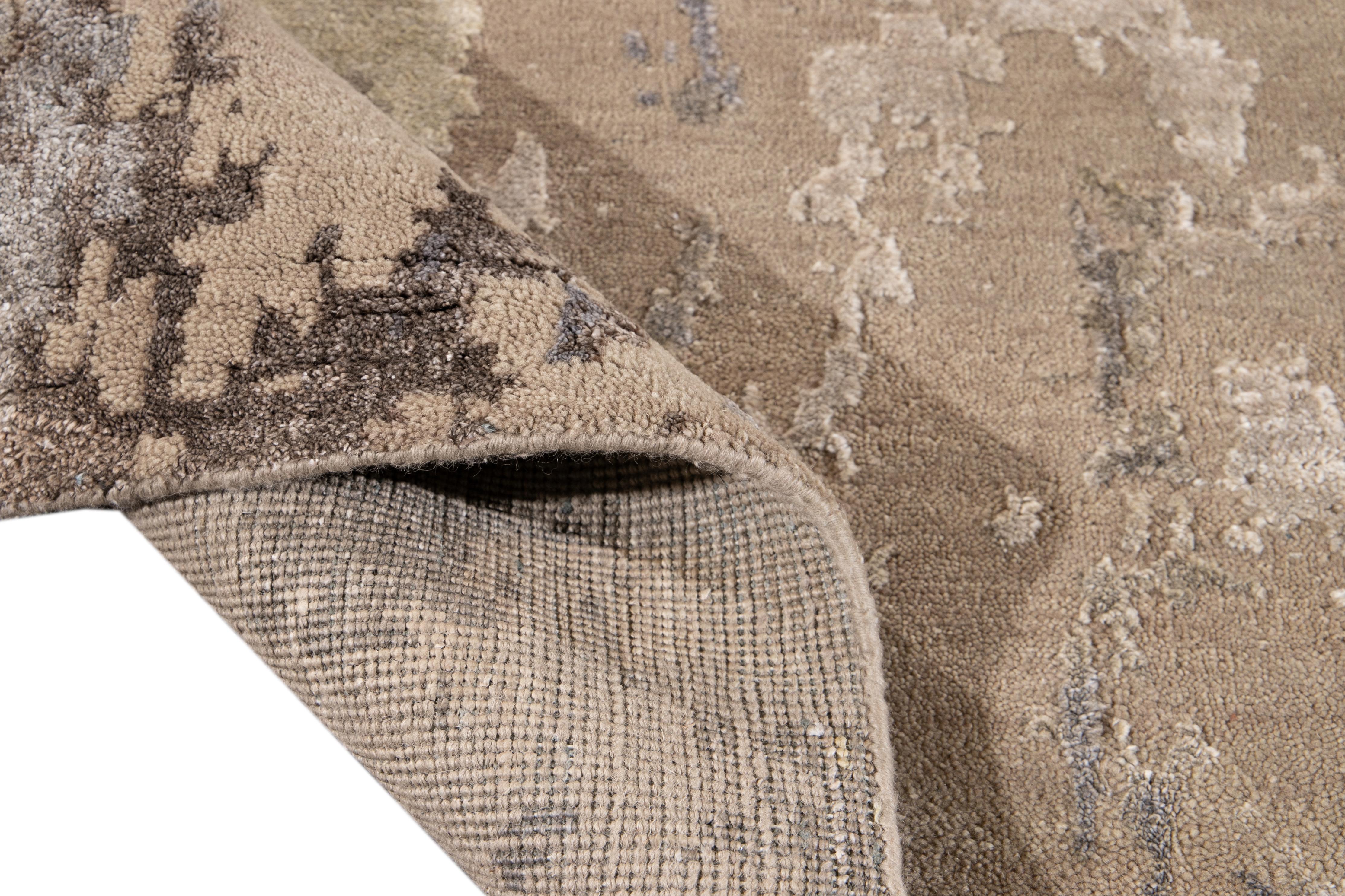 Magnifique tapis contemporain en laine et en soie, fait à la main, avec un champ beige. Ce tapis présente des accents de bleu, de gris et d'ivoire dans un magnifique motif abstrait.

Ce tapis mesure : 10' x 14'.