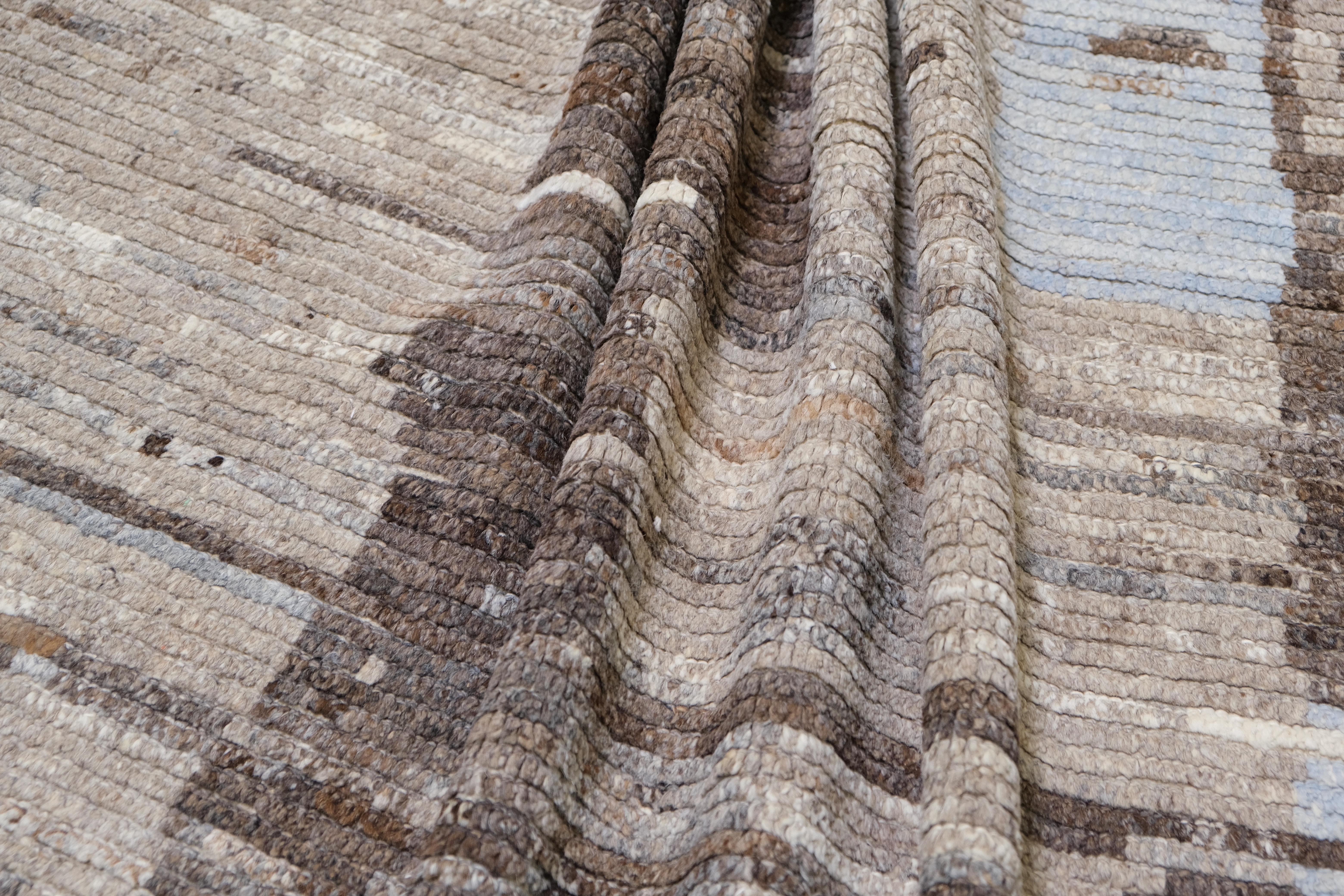 This exquisite hand-knotted wool rug, crafted in Afghanistan, features an abstract design inspired by organic textures and earthy tones. Measuring approximately 13' x 15'7'', this rug combines a contemporary artistic aesthetic with traditional