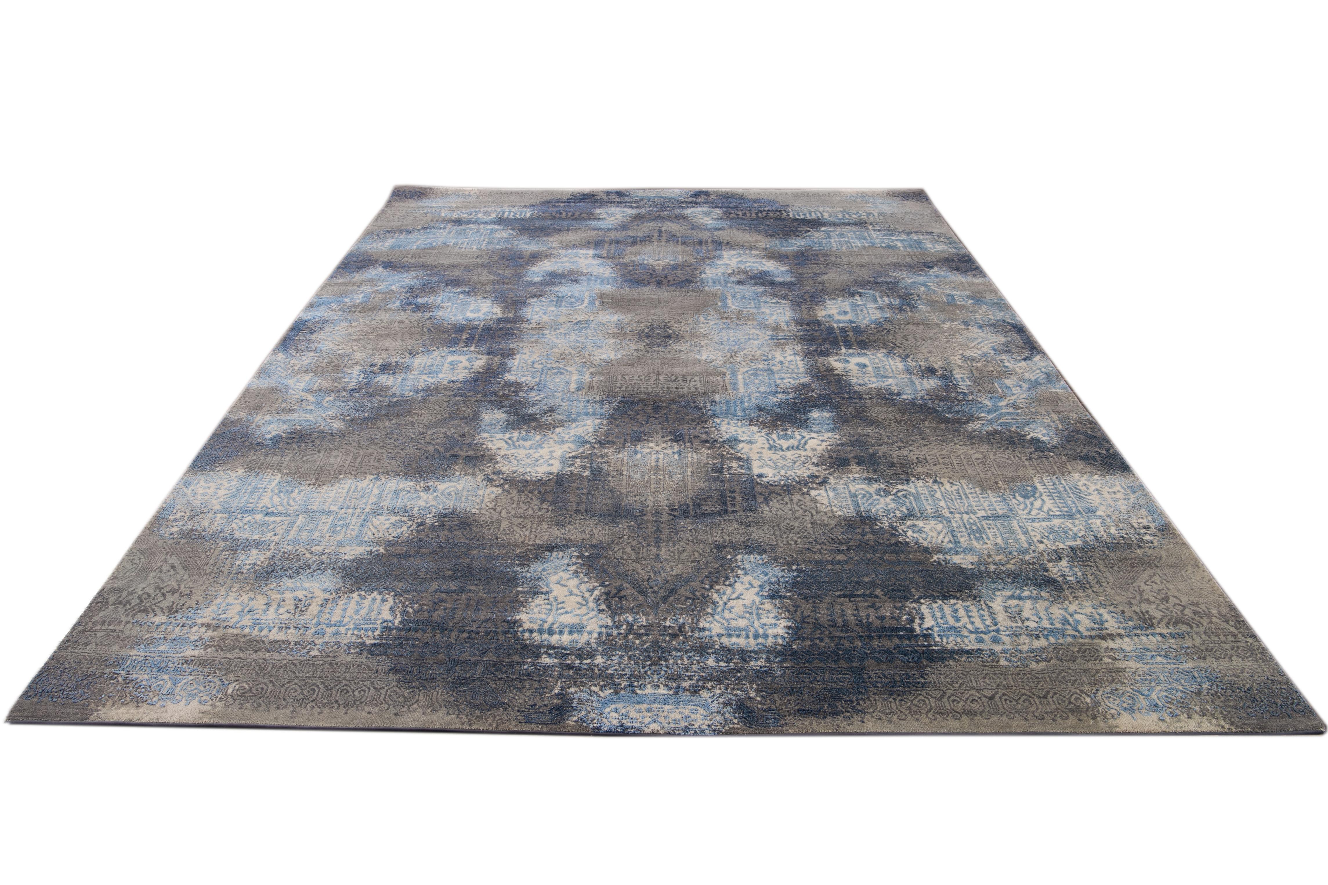 Questo sofisticato tappeto in lana e seta presenta un accattivante disegno astratto ornato da eleganti sfumature di grigio e blu, che si fondono con le seducenti tonalità del beige.

Questo tappeto misura 8'11