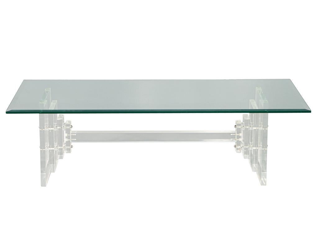 Step into a realm of mid-century elegance with this exquisite Karl Springer-inspired acrylic cocktail table, a testament to the transformative power of geometric design. Its striking squared base, composed of stacked lucite panels, creates an