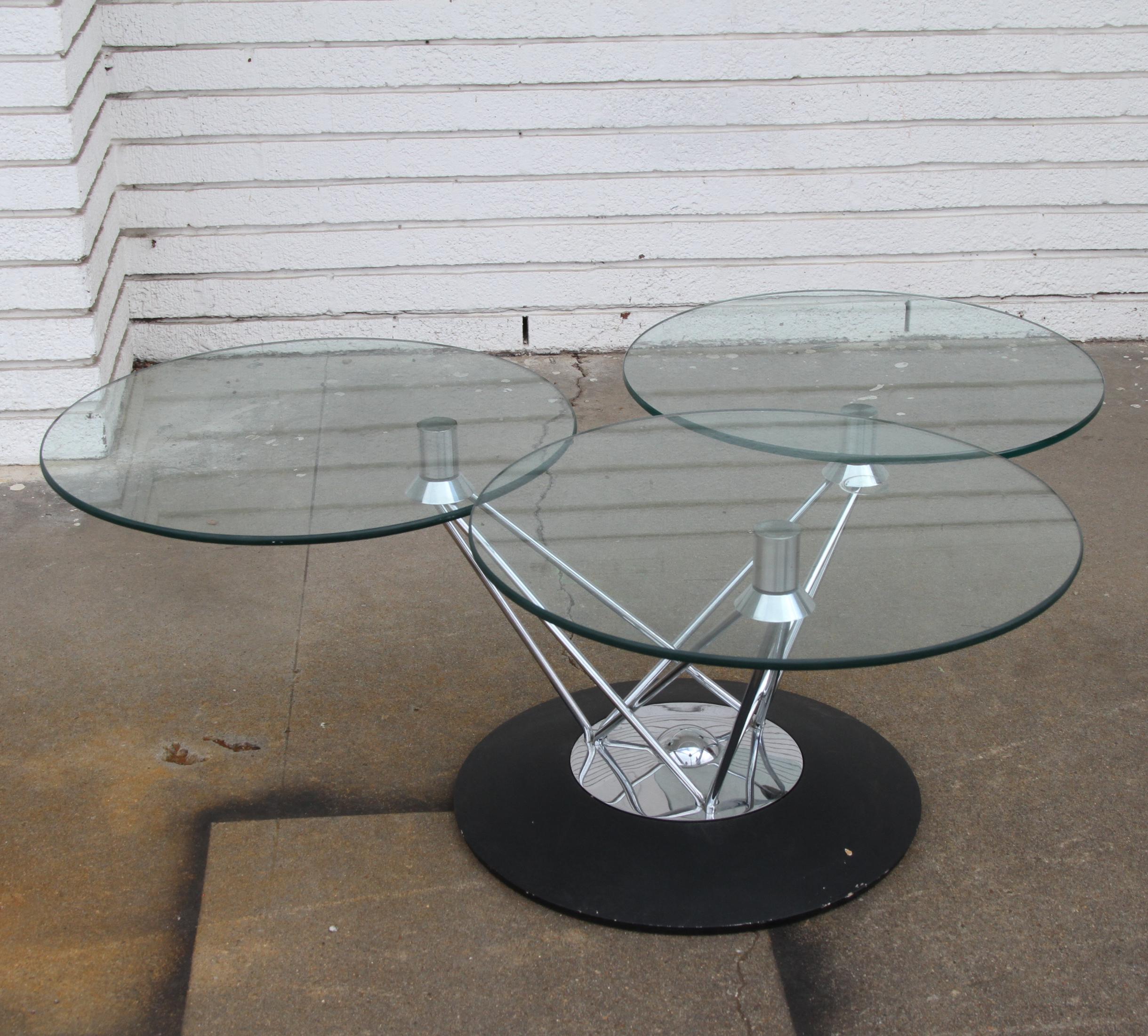 3 Piece Modern Cyclone Glass Table 

American, circa 1970
 Sculputural concave black enamel base capped with a circular polished chrome cap with a finial of the same material emanating from its center. Three angled cylindrical brass rods connect the
