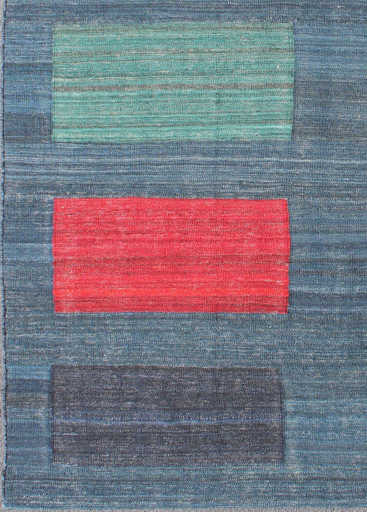 This flat-weave Kilim bears a repeating box design. Set on a gray and steal blue background, accent colors include green, maroon, red, charcoal, dark blue, cream, and pinkish color. This rug would be beautiful in a modern interior.
Measures: 6' x