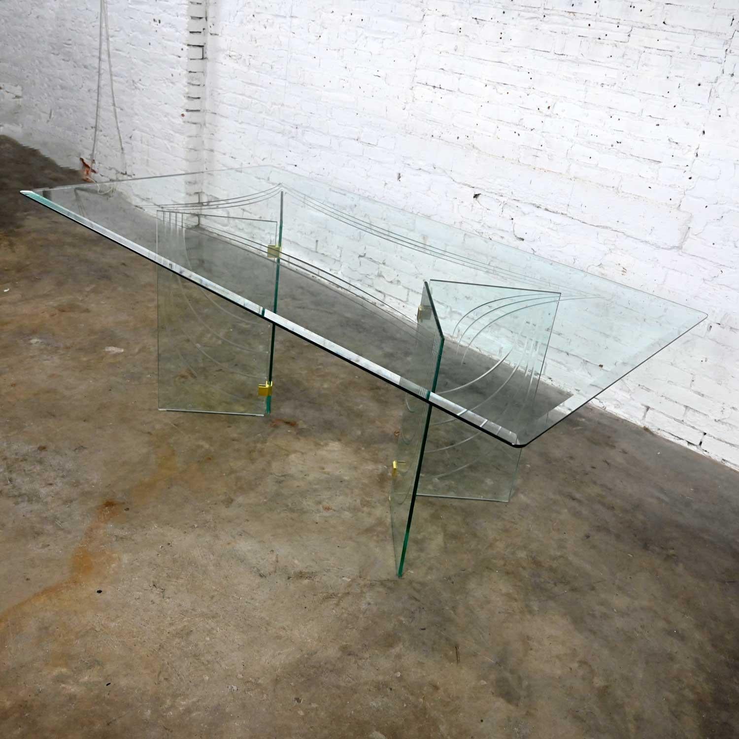 Stunning vintage modern all glass dining table V double pedestal base with incised draped design and four polished brass plated aluminum connectors in the style of Pace. Beautiful condition, keeping in mind that this is vintage and not new so will