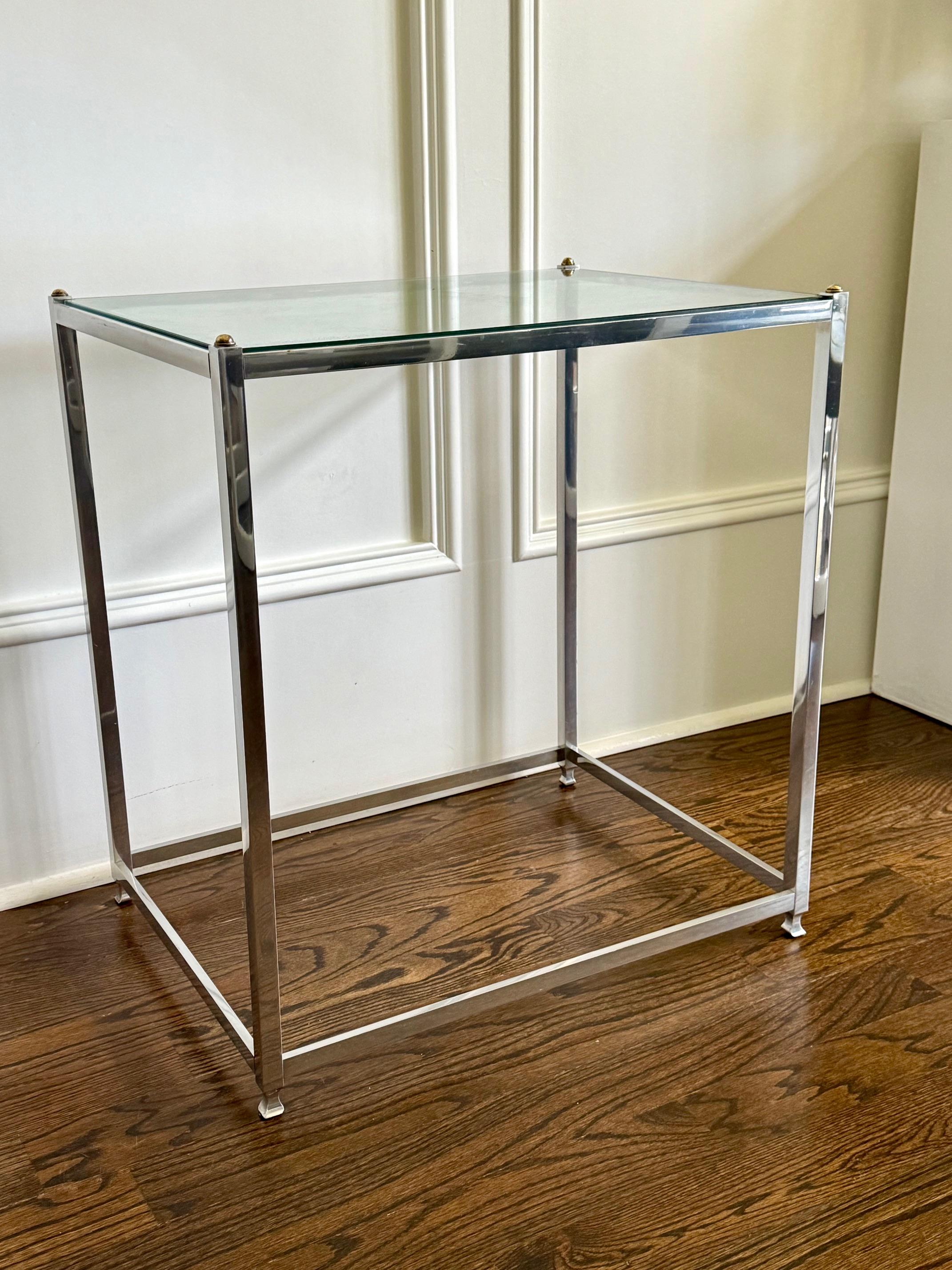 Tavolino moderno di John Vesey (1924-1999) degli anni '60 circa. Realizzato in alluminio massiccio di tipo industriale con accenti in ottone, il tavolo ha una forma minimalista con piano in vetro intagliato incastonato nella struttura. I laconici