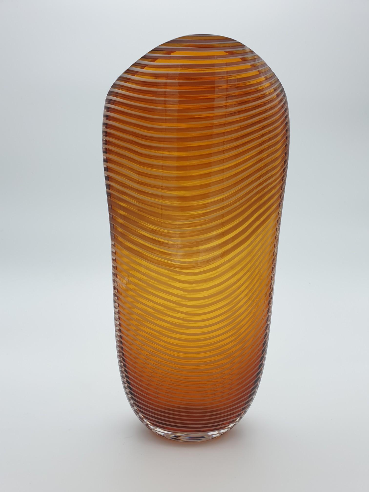 This modern stylish vase has been handmade in Murano by the glass-factory Gino Cenedese e Figlio. The vase is a beautiful warm amber color and has a milky colored spiral going all around; its cross section is oval and the lip is cut diagonally. The