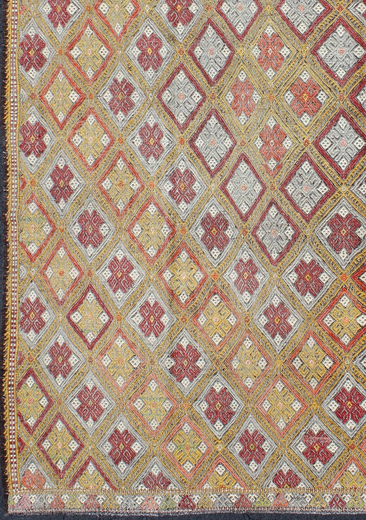 Woven during the mid-20th century in Turkey, this designer Embroidered Kilim is decorated with geometric motifs rendered in a diamond pattern. This flat-woven Kilim contains various multi-colors, and makes the perfect accent piece to any