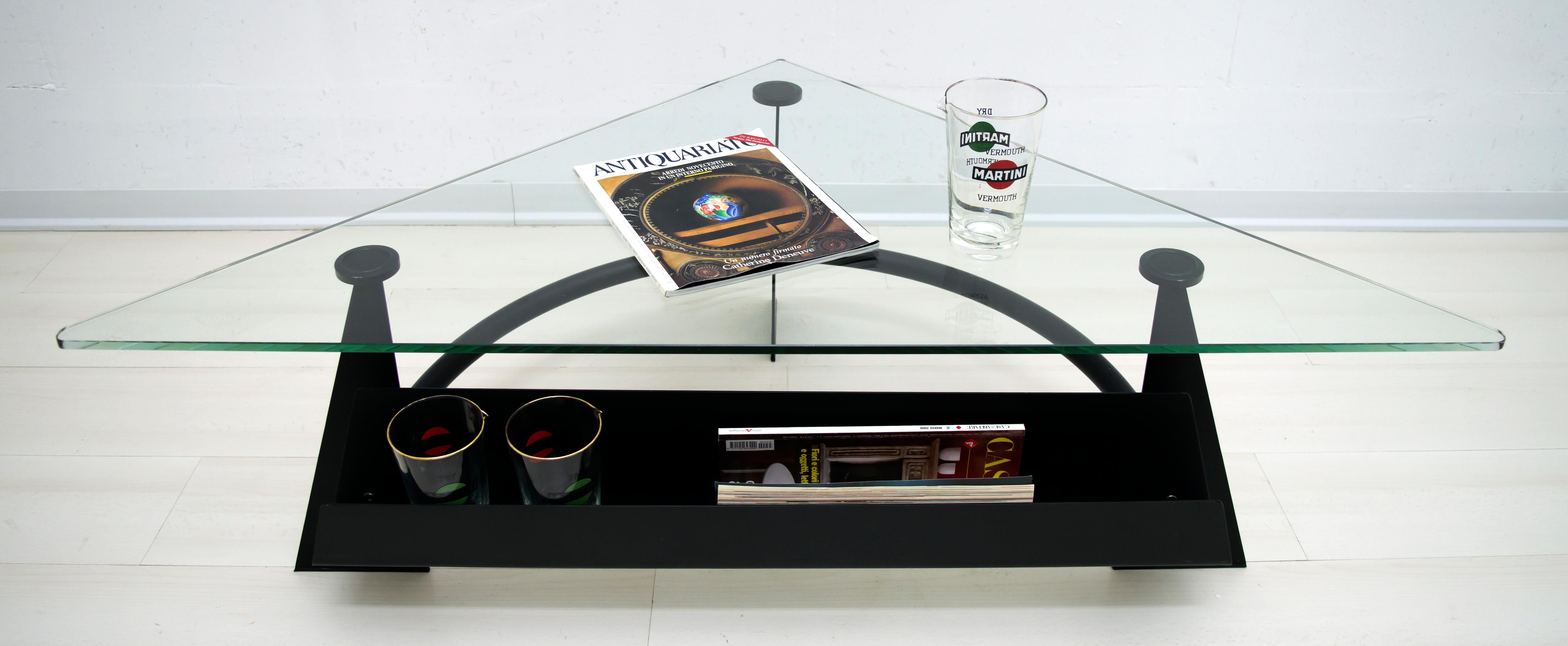 Table basse italienne moderne, base en métal noirci avec porte-revues et plateau en verre de forme triangulaire, 1990.

