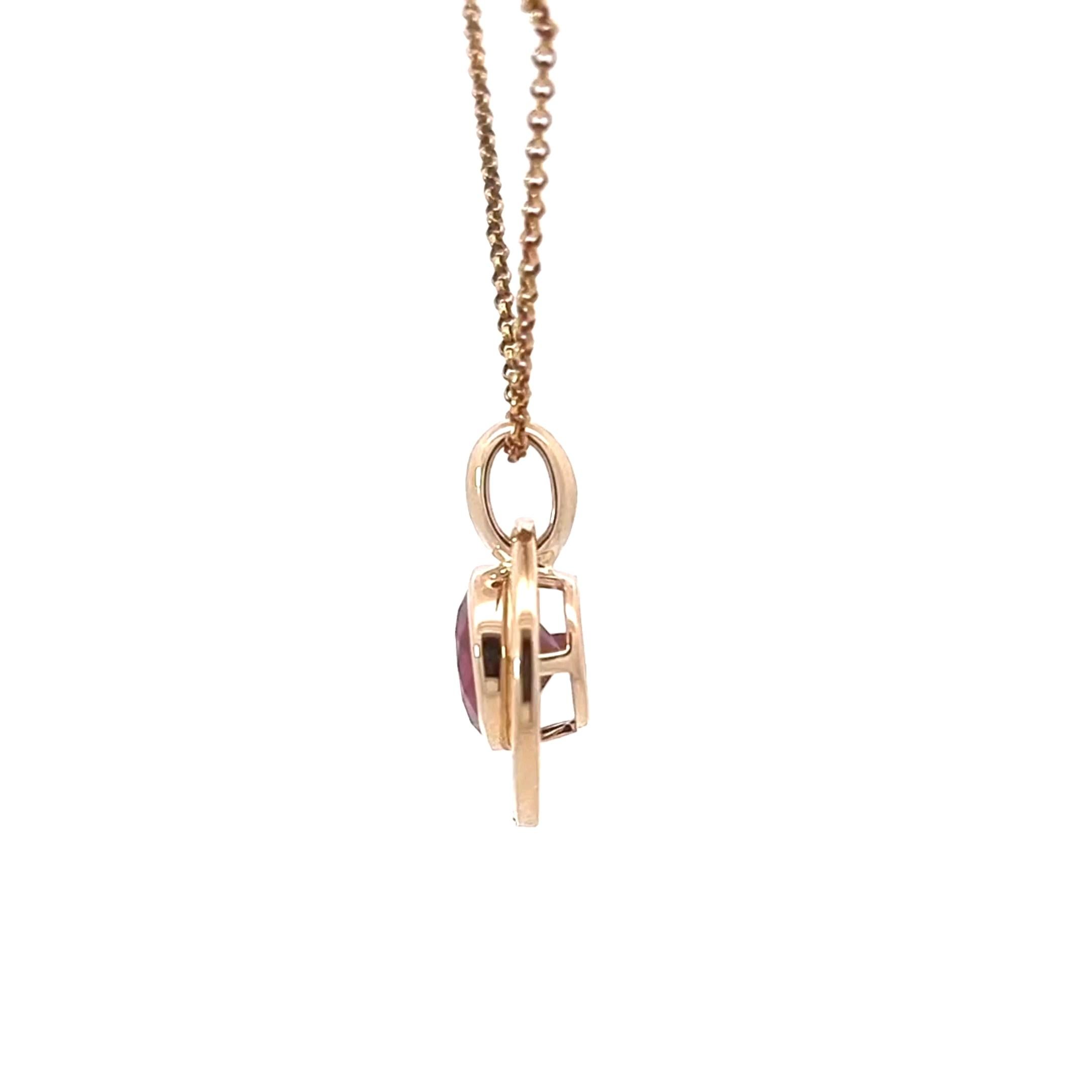 Ce pendentif élégant en or jaune 14 carats offre un mélange parfait de design moderne et d'élégance intemporelle. En son centre se trouve un captivant grenat rond de Tanzanie, serti en chaton pour mettre en valeur sa teinte rouge feu profonde et sa