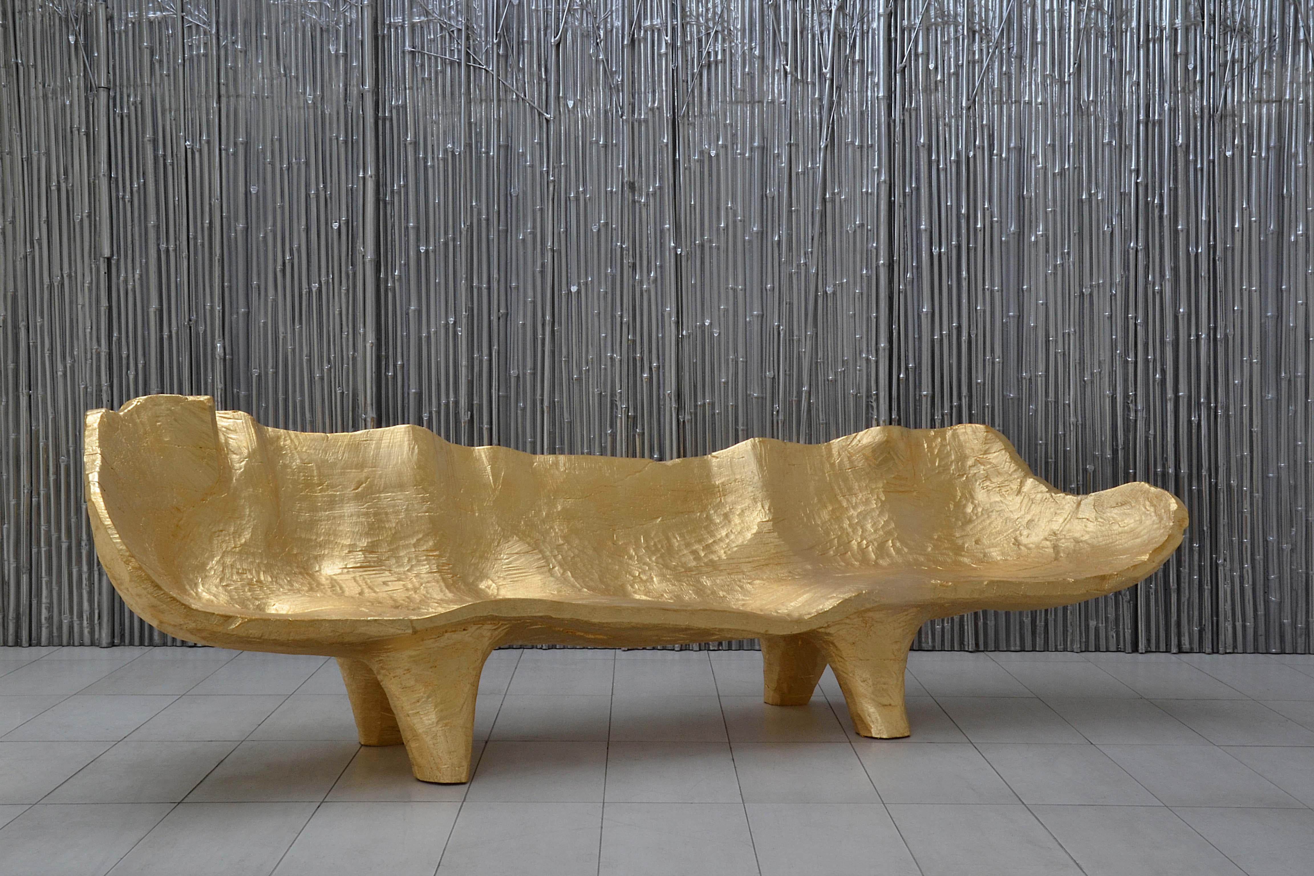 Sculptured sofa made by Andrea Salvetti for Dilmos Milano.
The sofa is cut from a solid piece of wood, carefully shaped by the hand of the designer using machete knives to evoke a luxurious sofa. The surface is completely covered in gold