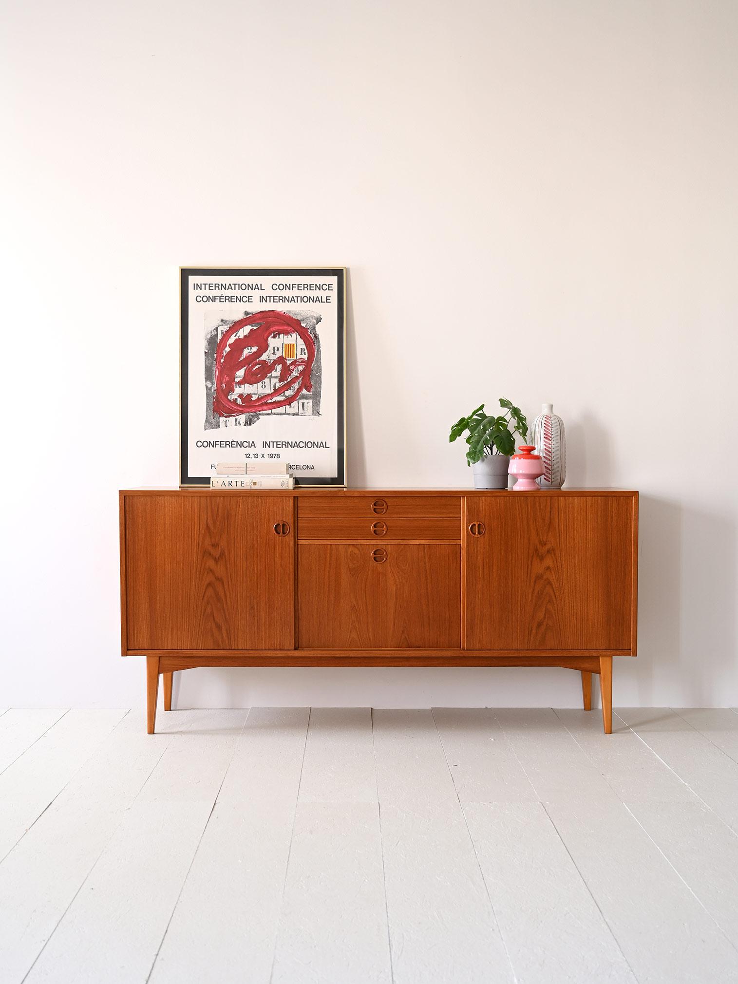 Vintage 1960s Scandinavian sideboard.

This elegant Swedish-designed cabinet is divided into three equally sized sections; on the sides is a storage compartment with a sliding door, respectively, and in the center are two small drawers and a